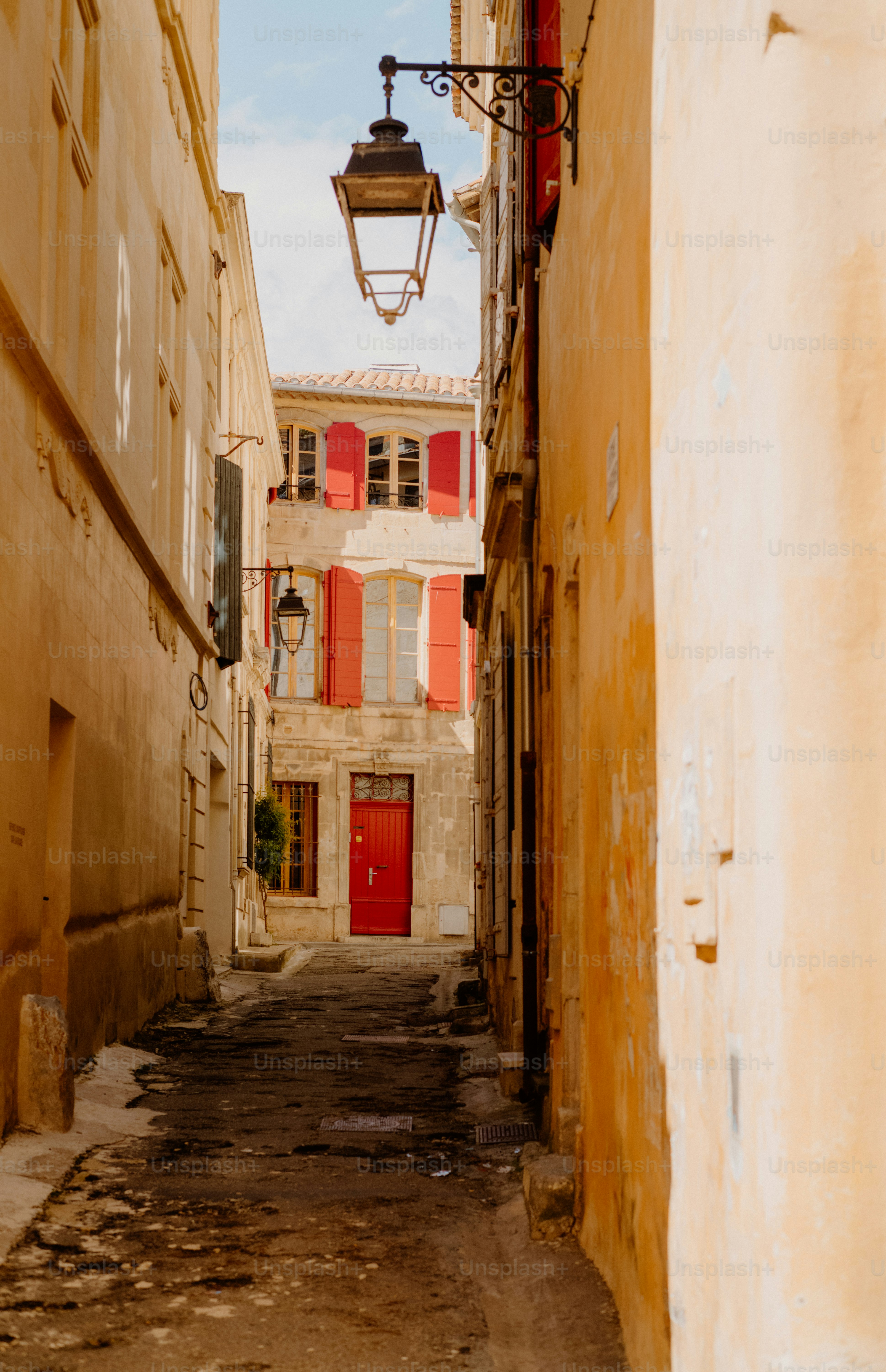 Narrow european street with red door and shutters.