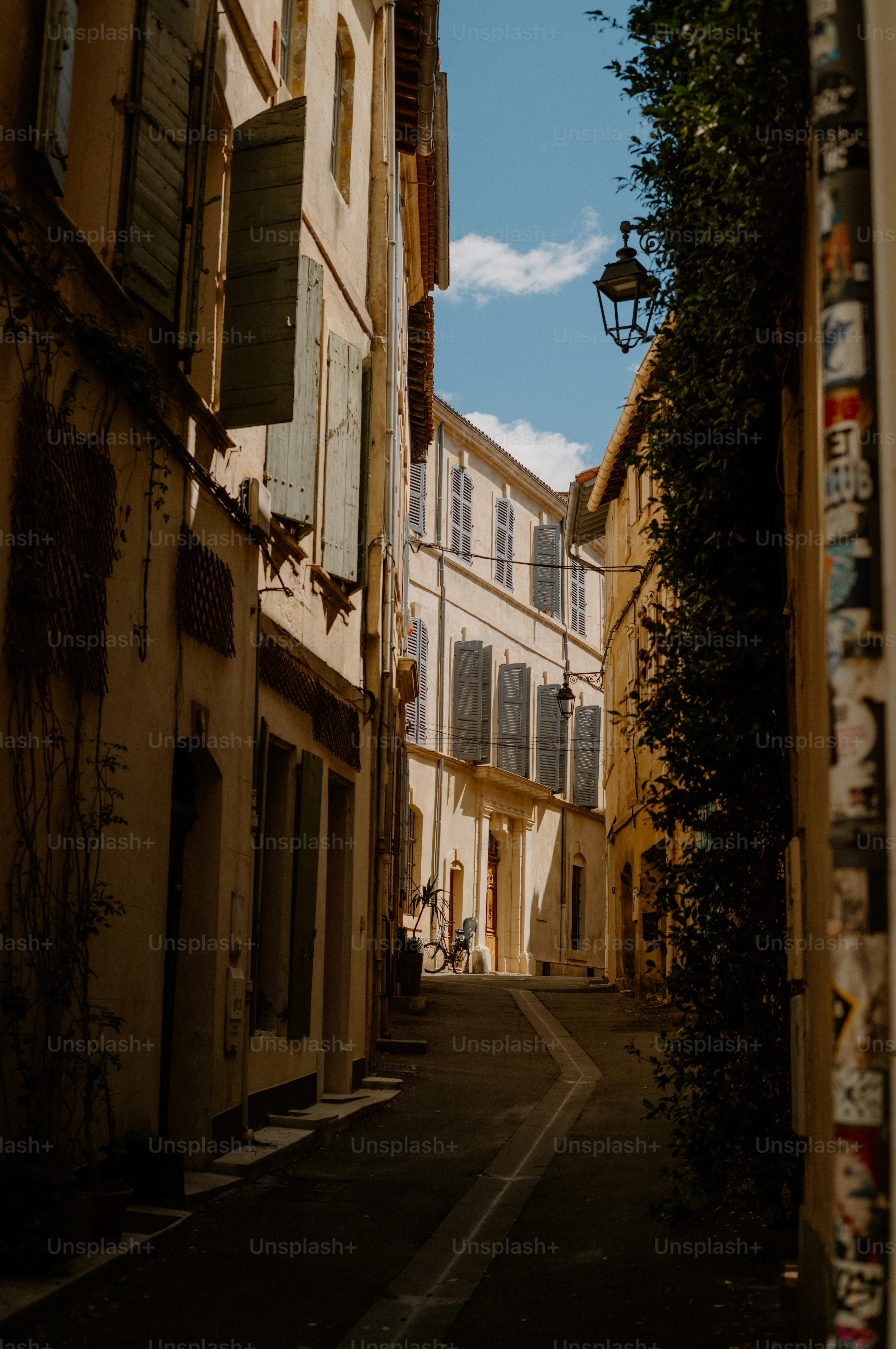 Narrow, sunlit european alleyway with tall buildings and shutters.