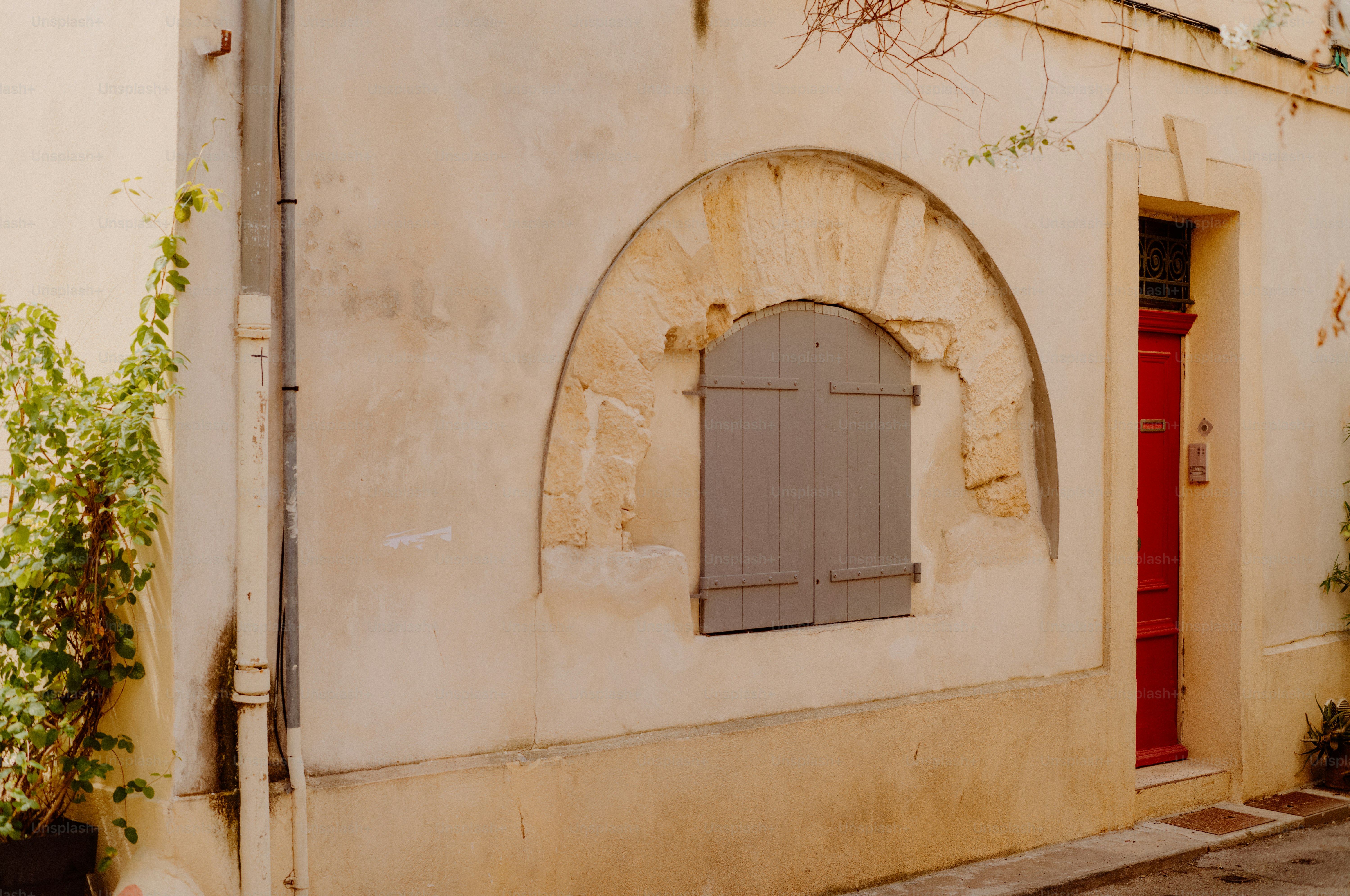 A rustic arched window with gray shutters on a building.