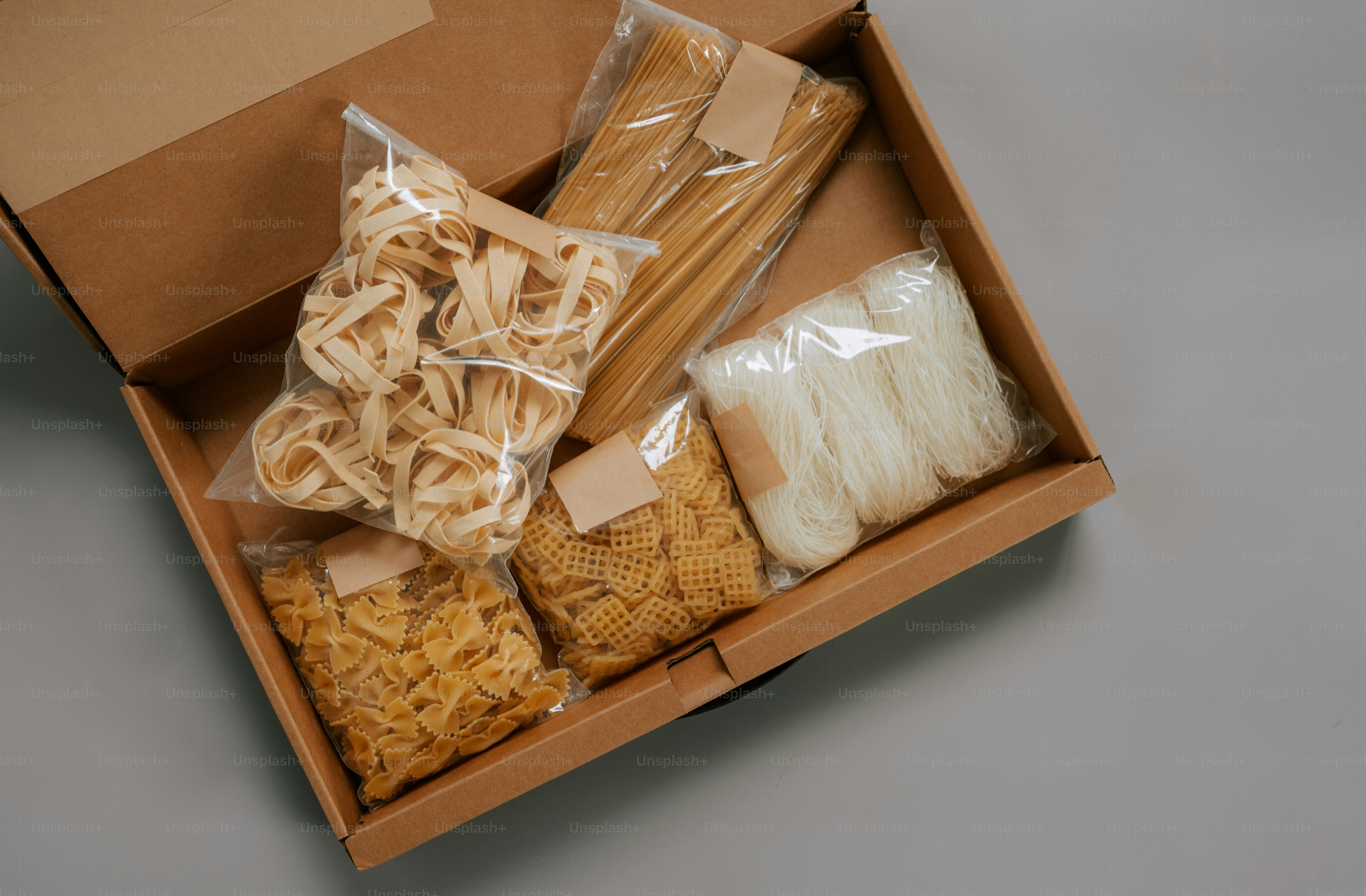 Vari tipi di pasta e noodles confezionati dentro una scatola di cartone aperta