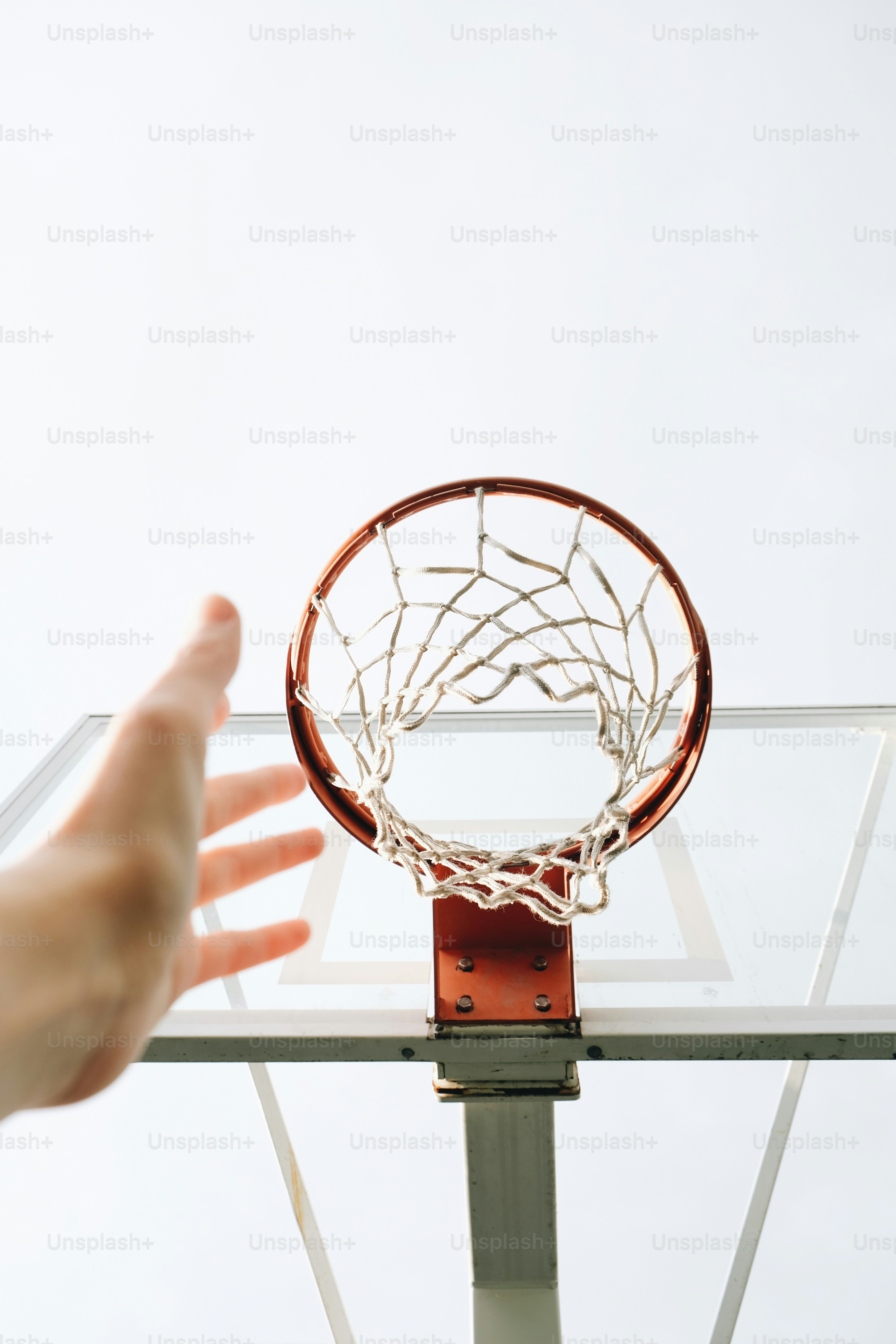 Mano che si allunga verso un canestro da basket da sotto