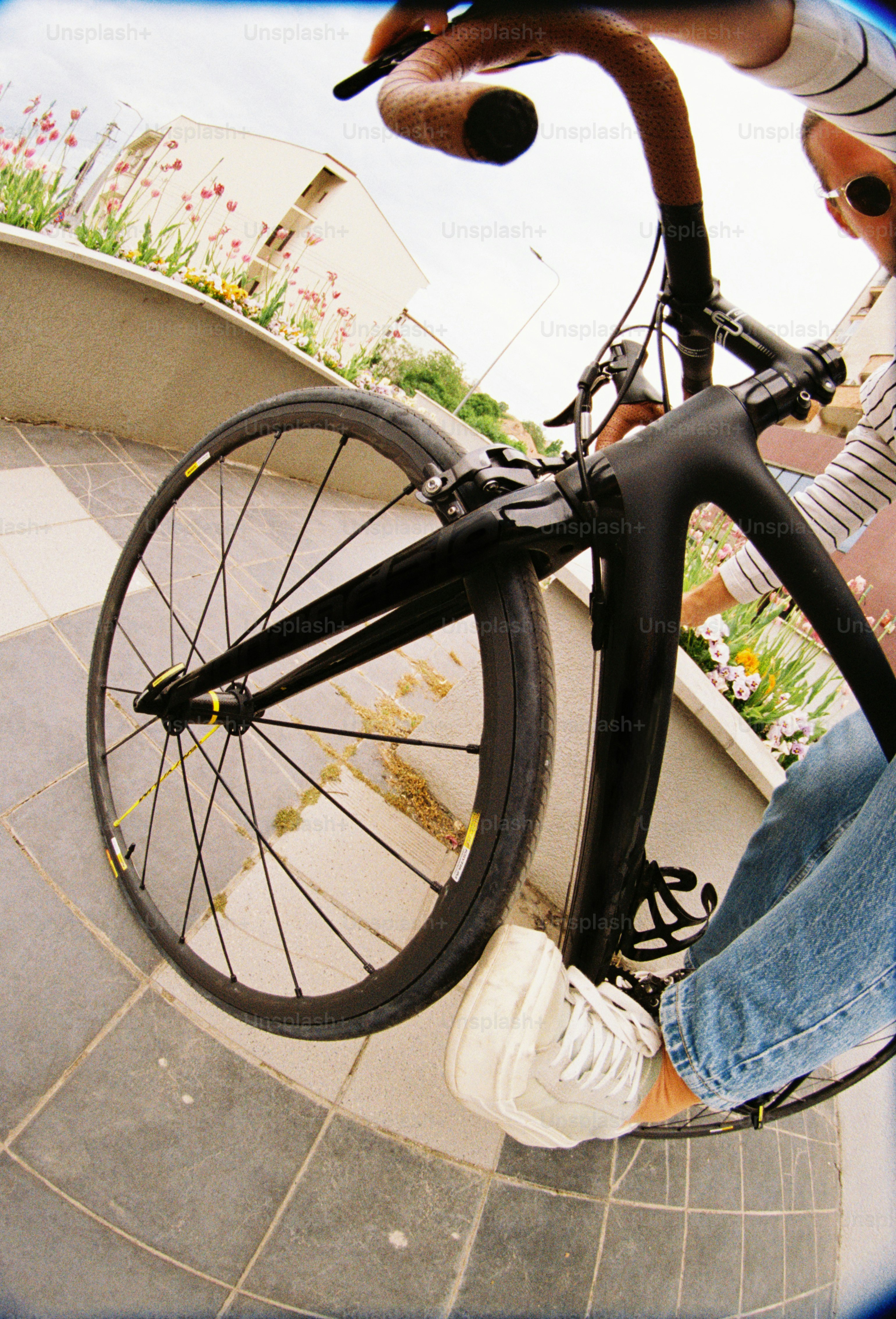 黒い自転車に乗ったサイクリストが曲がったタイルの路面を走り抜ける。