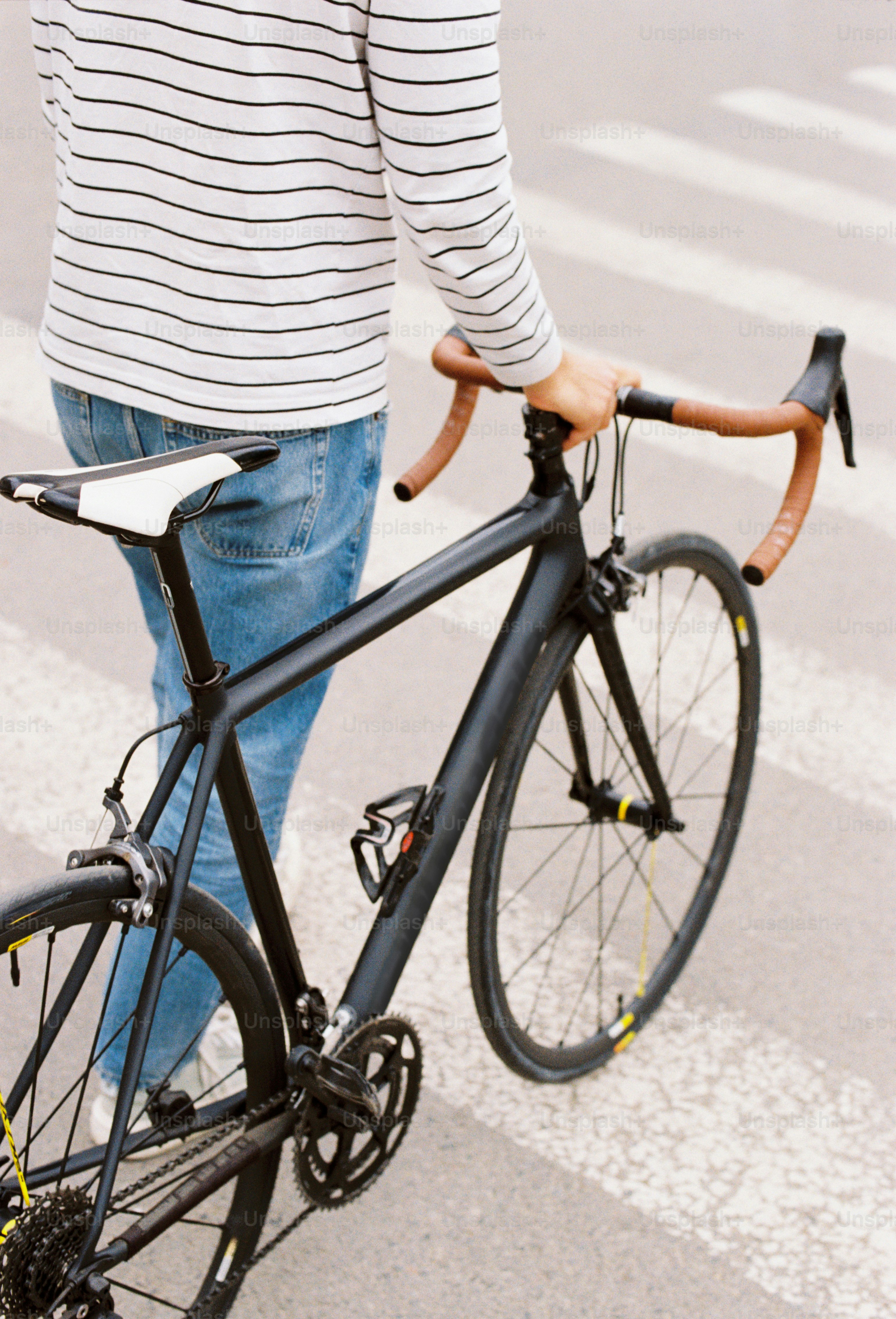 黒い自転車で縞模様の横断歩道を歩いている人物。