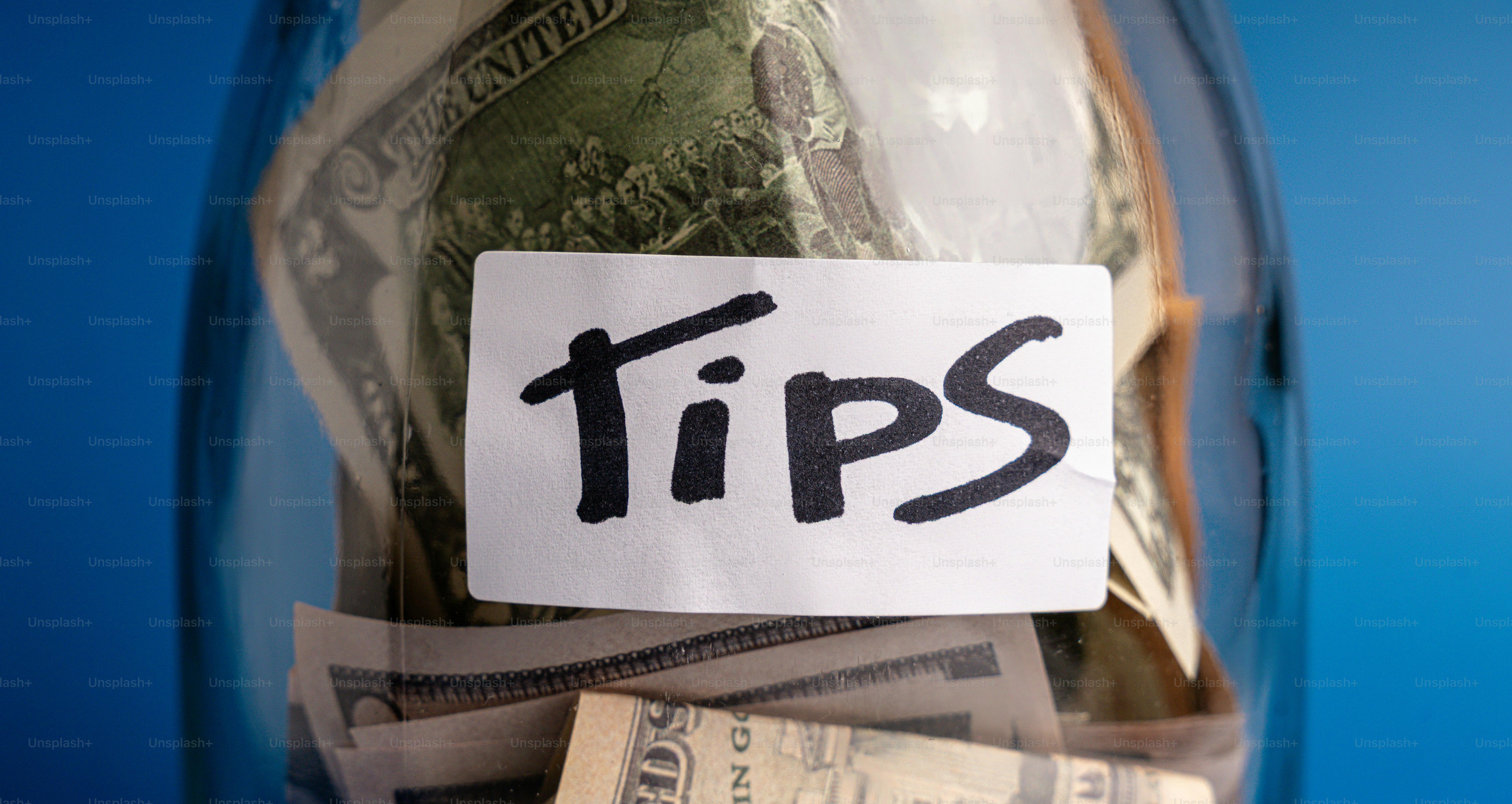 A glass jar filled with money labeled "tips".