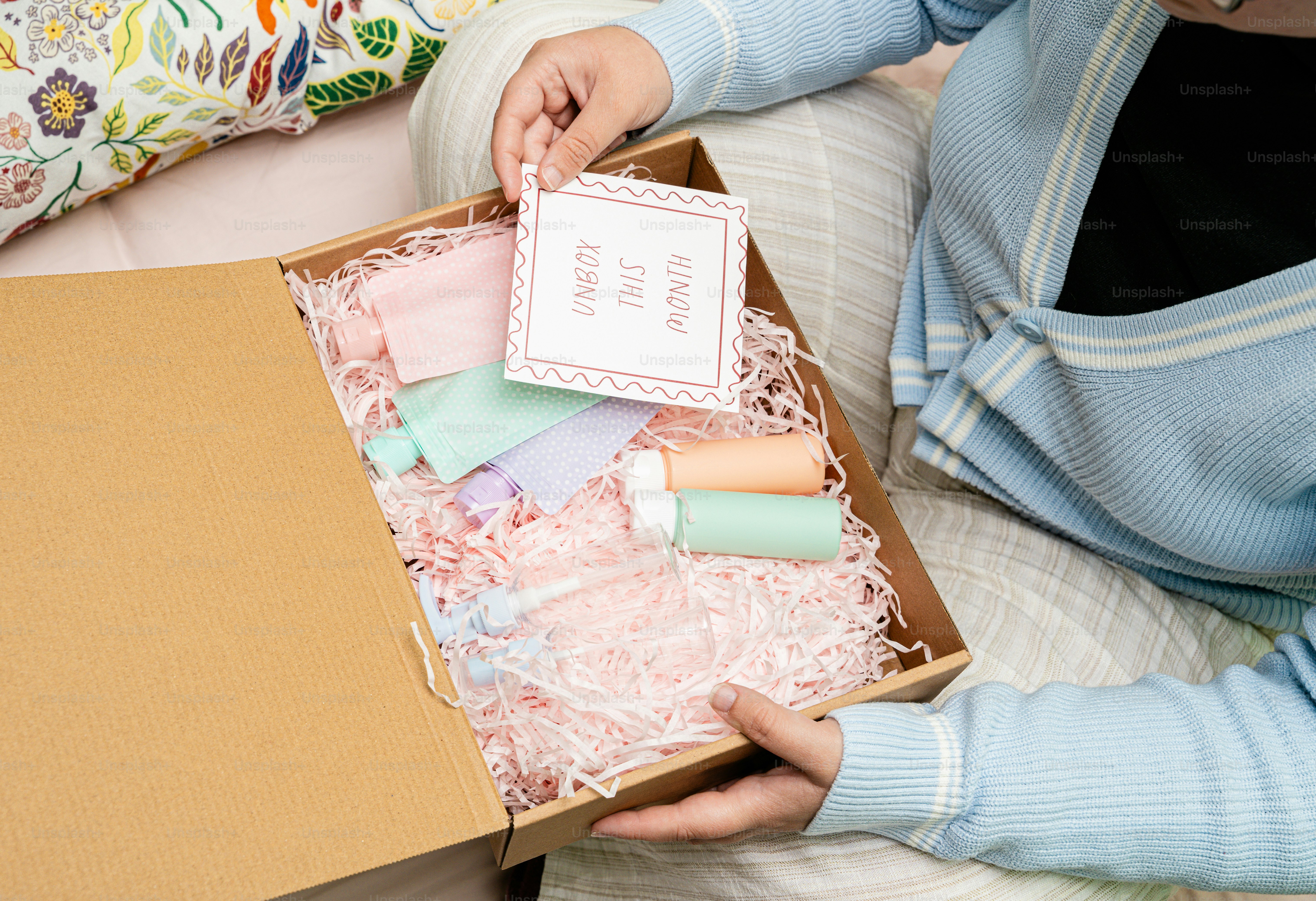 Orang yang membuka kotak hadiah dengan produk kecantikan pastel.