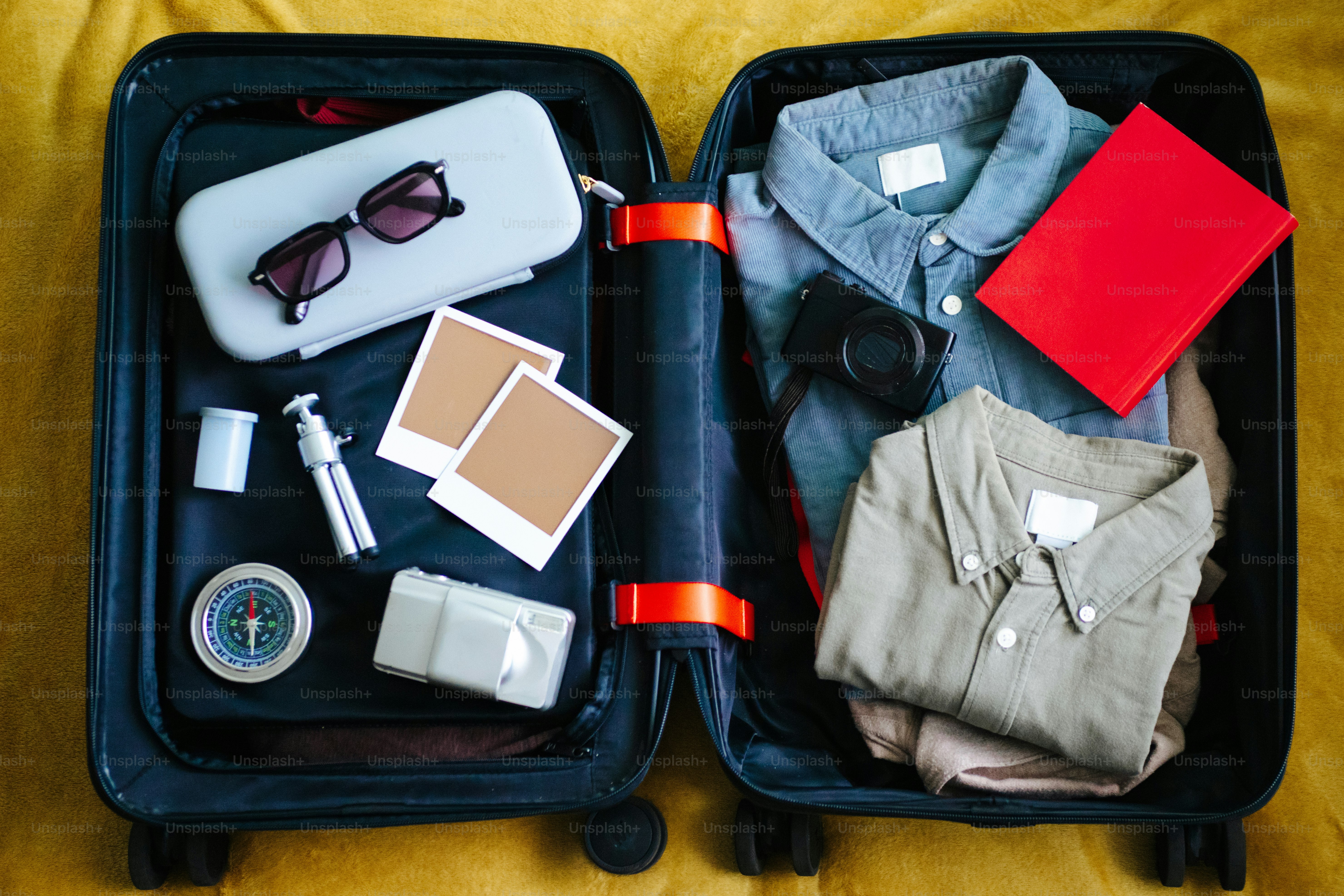 服やカメラ、旅行必需品が詰まったオープンスーツケース。
