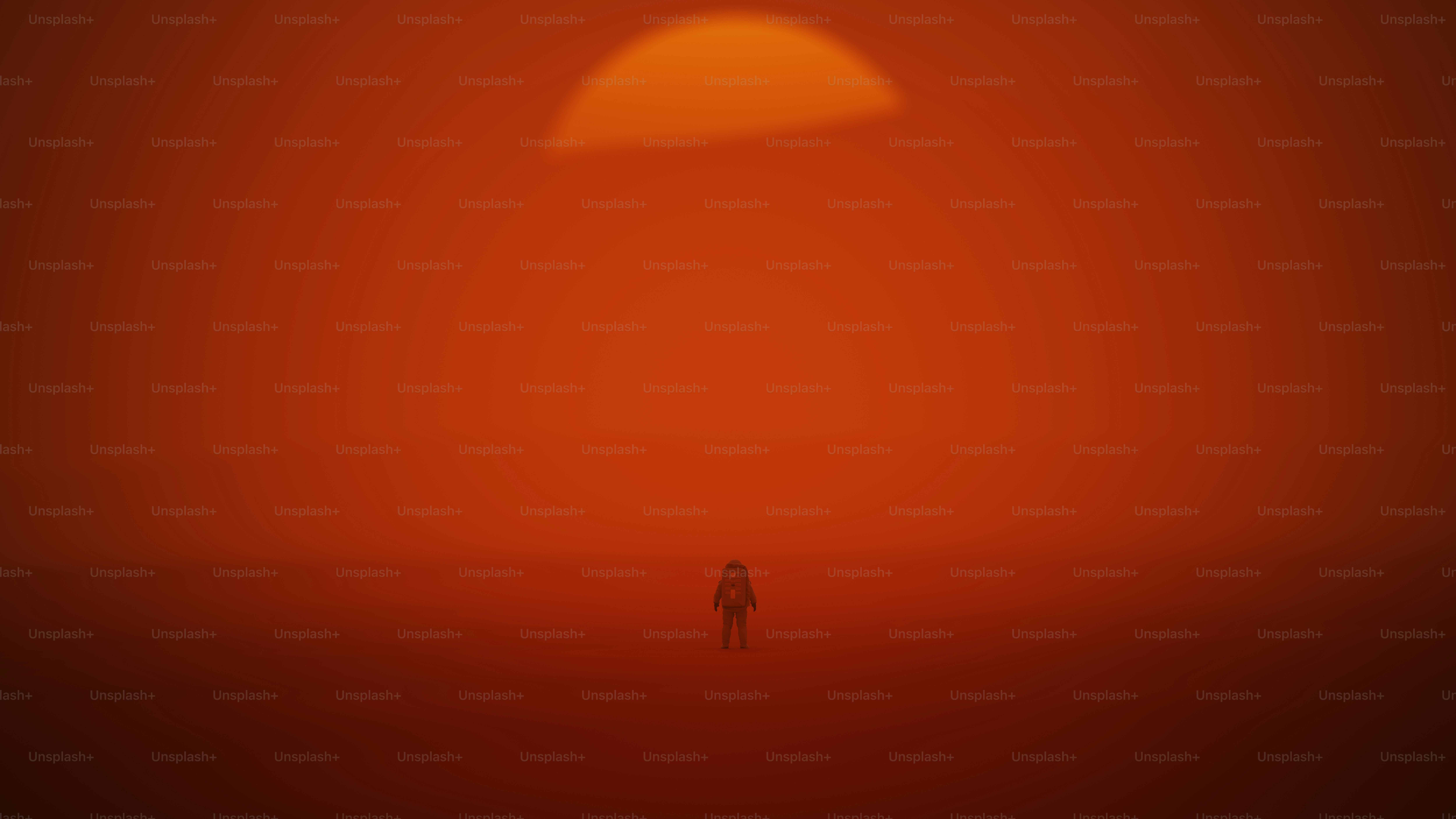 Una figura solitaria si erge contro un vasto tramonto arancione nel deserto.