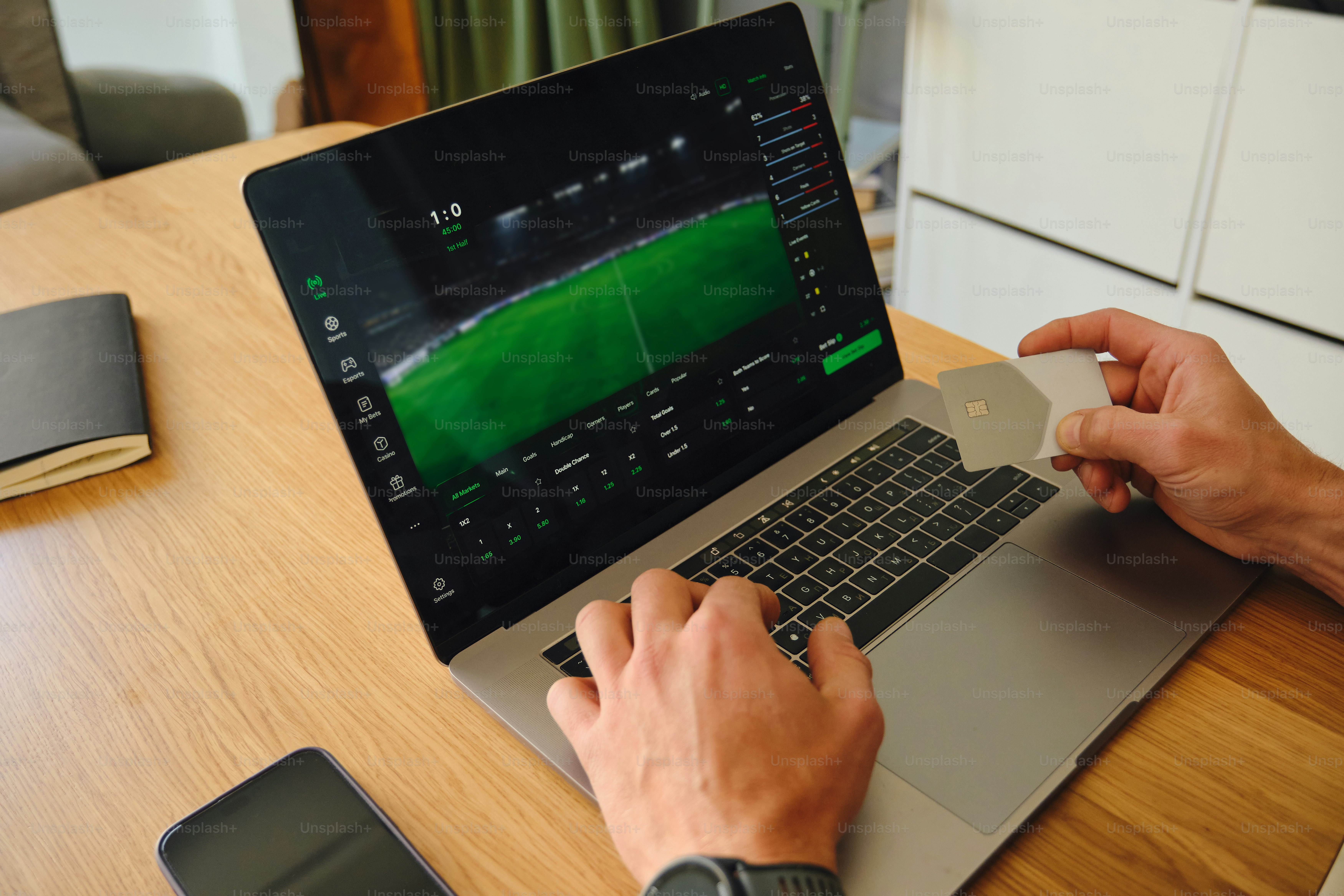Person using laptop with sports betting interface and credit card.