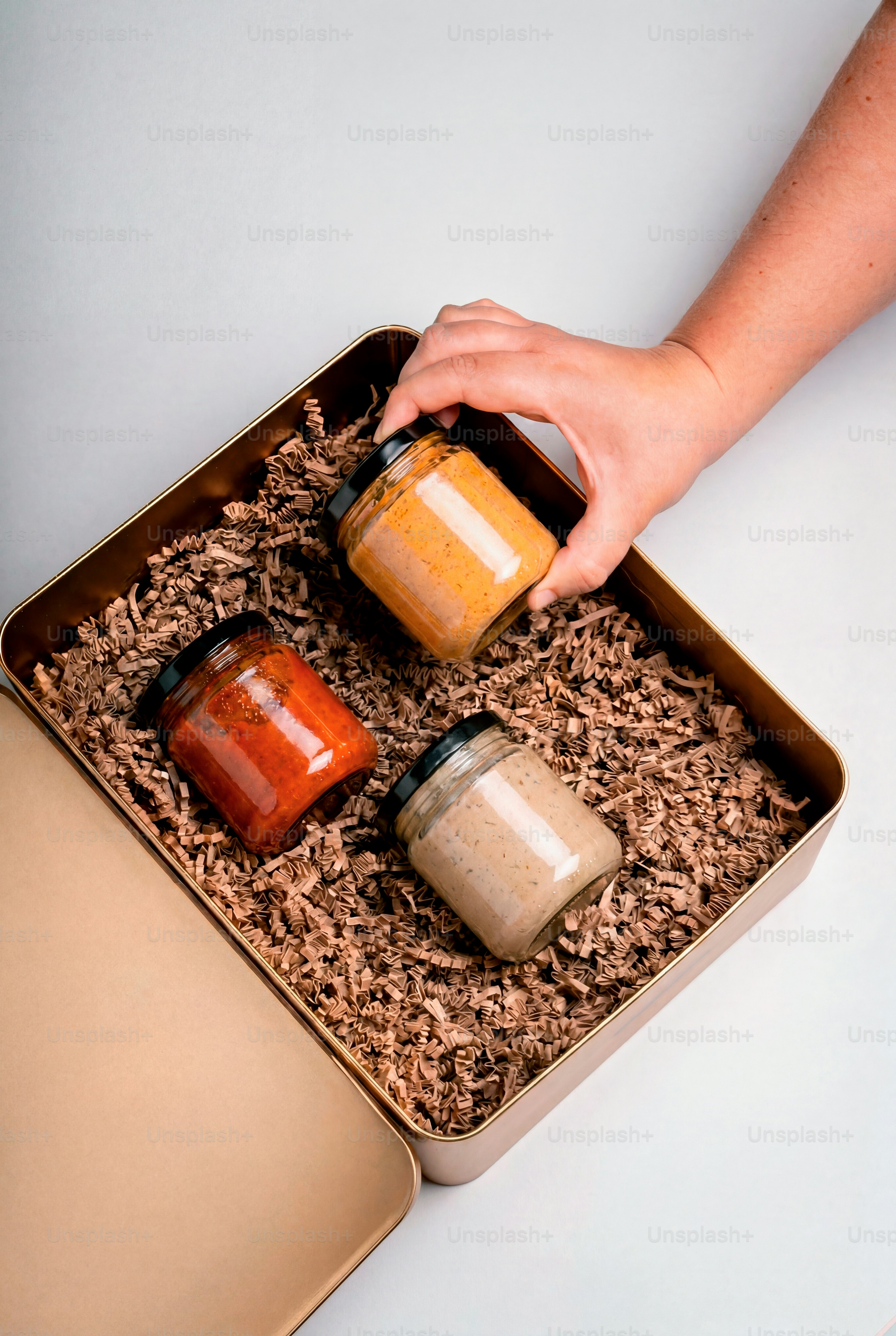 Hand placing jars into a gift box.