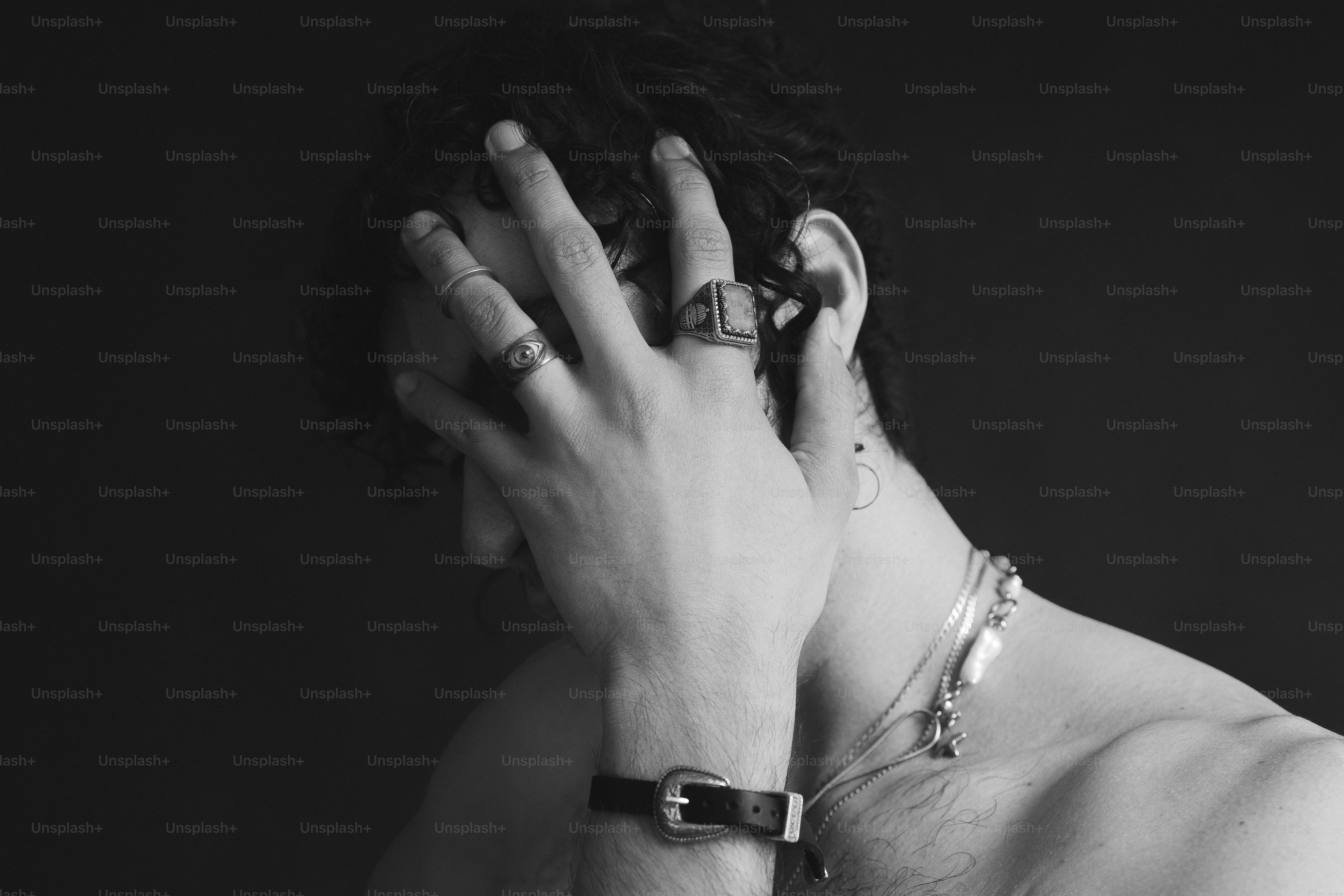 Monochrome person with hand on face, wearing rings and bracelet.