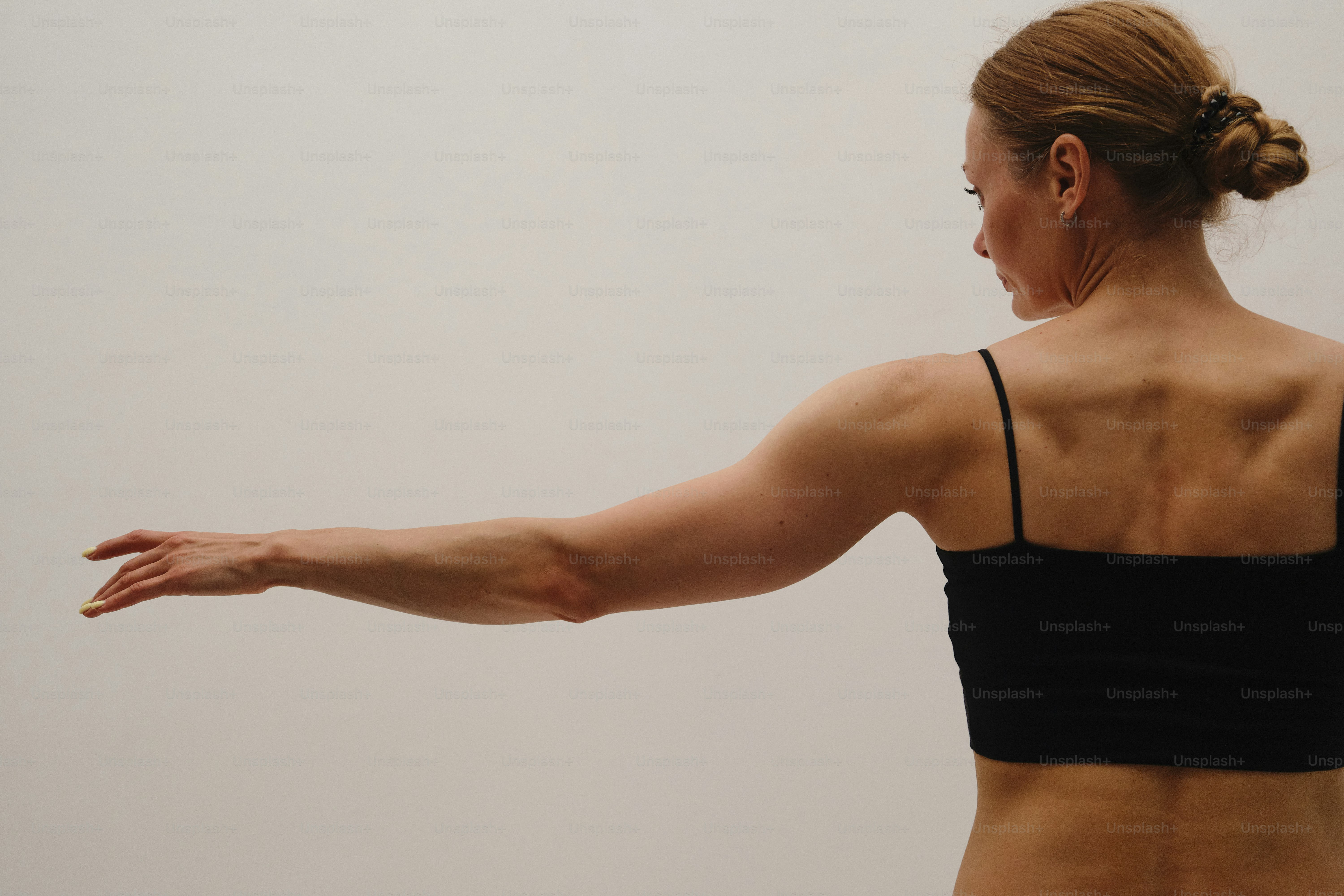 Woman extending her arm horizontally, viewed from behind. photo ...