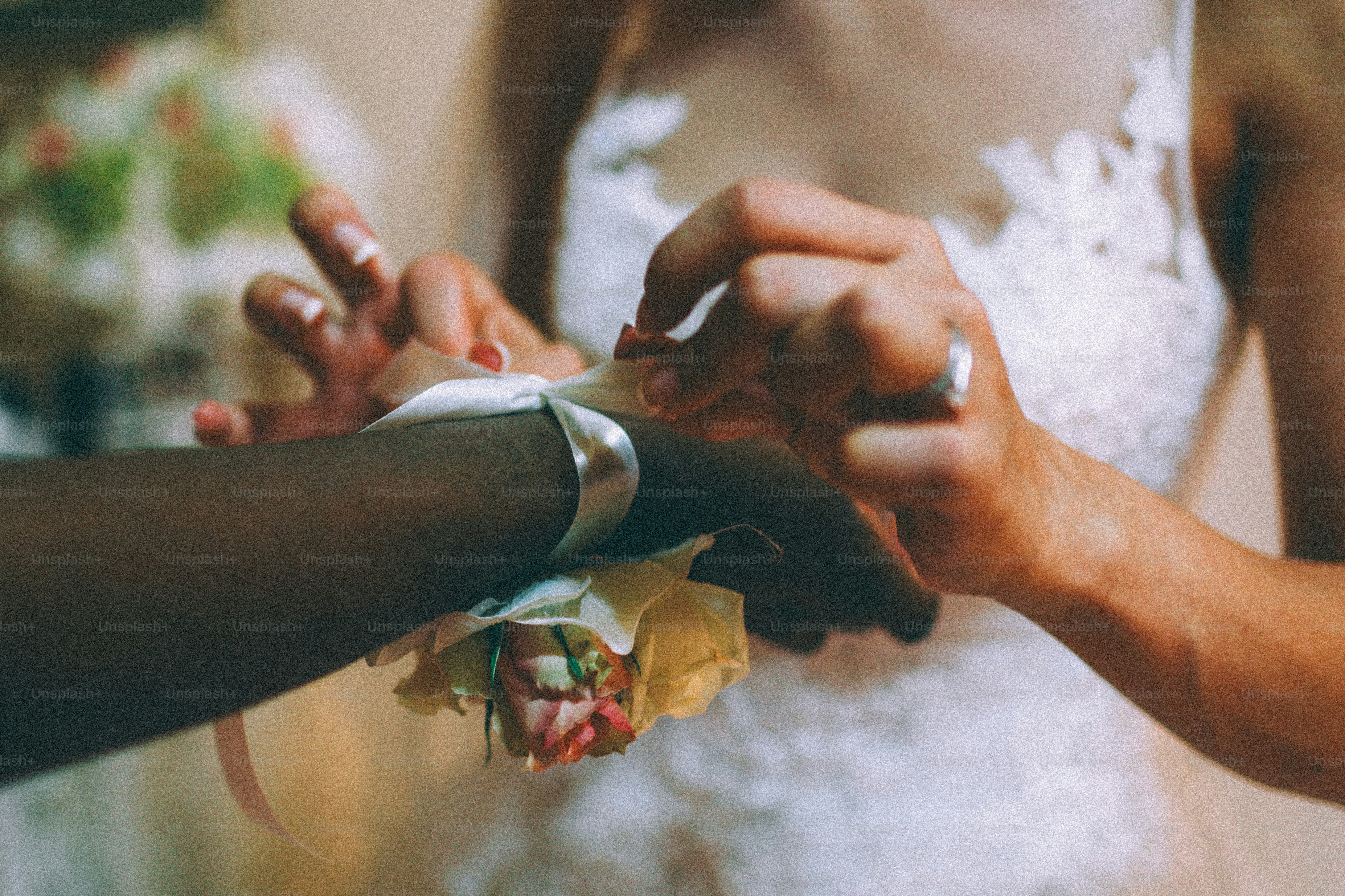 Hands attaching a floral corsage to a dark-skinned wrist.