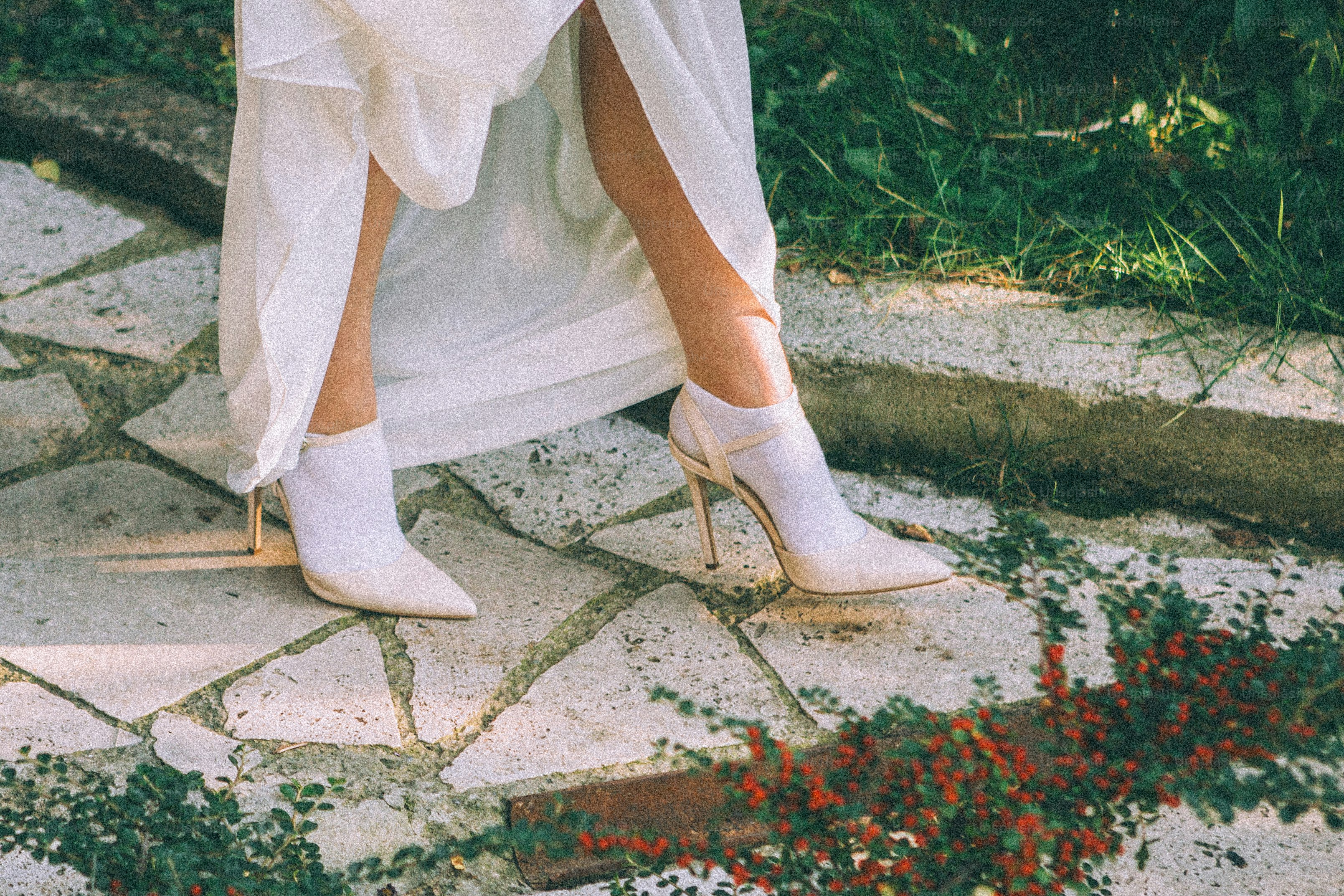 Woman in white dress and high heels on stone path.