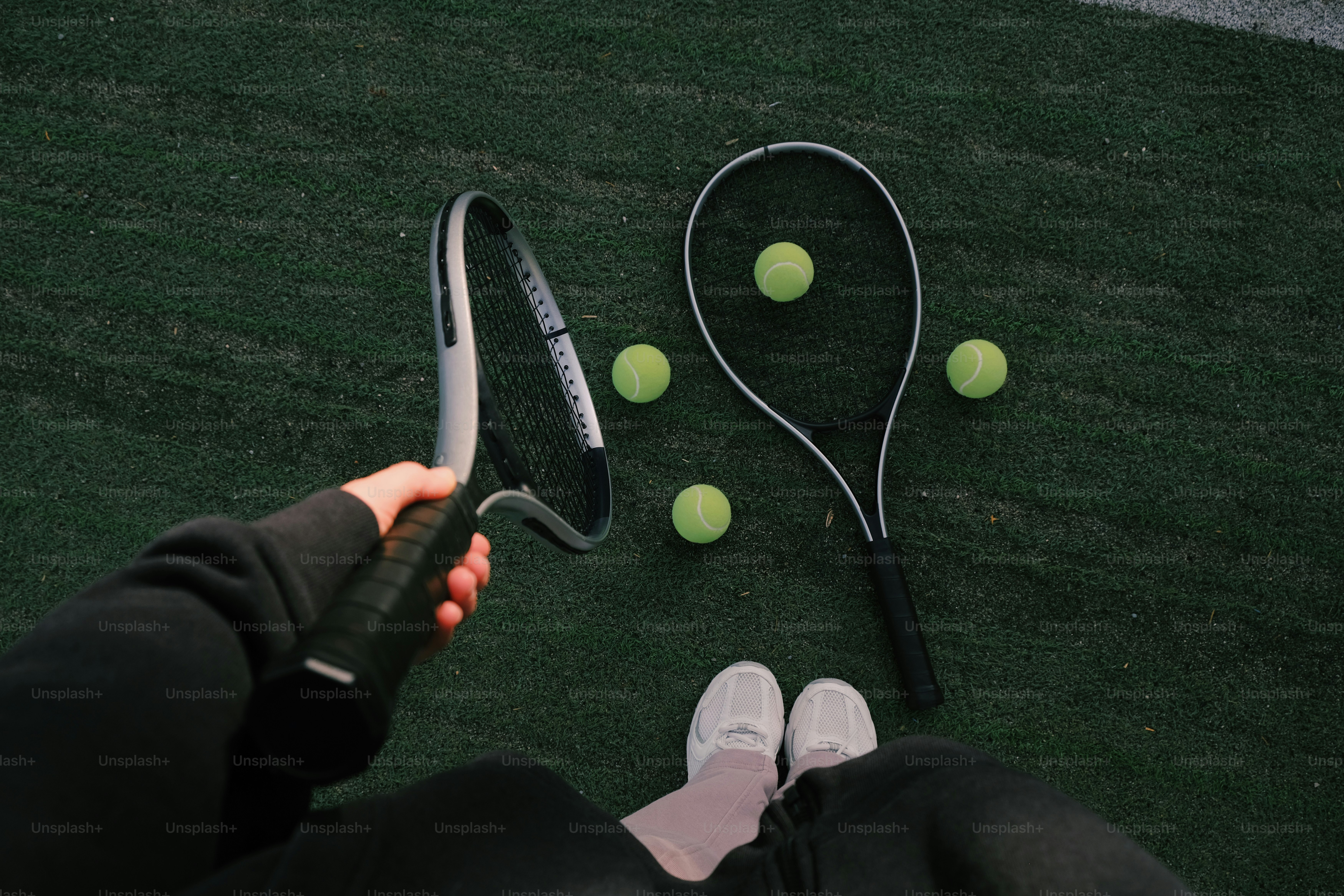 La persona tiene racchetta, altre racchette e palline sul campo da tennis