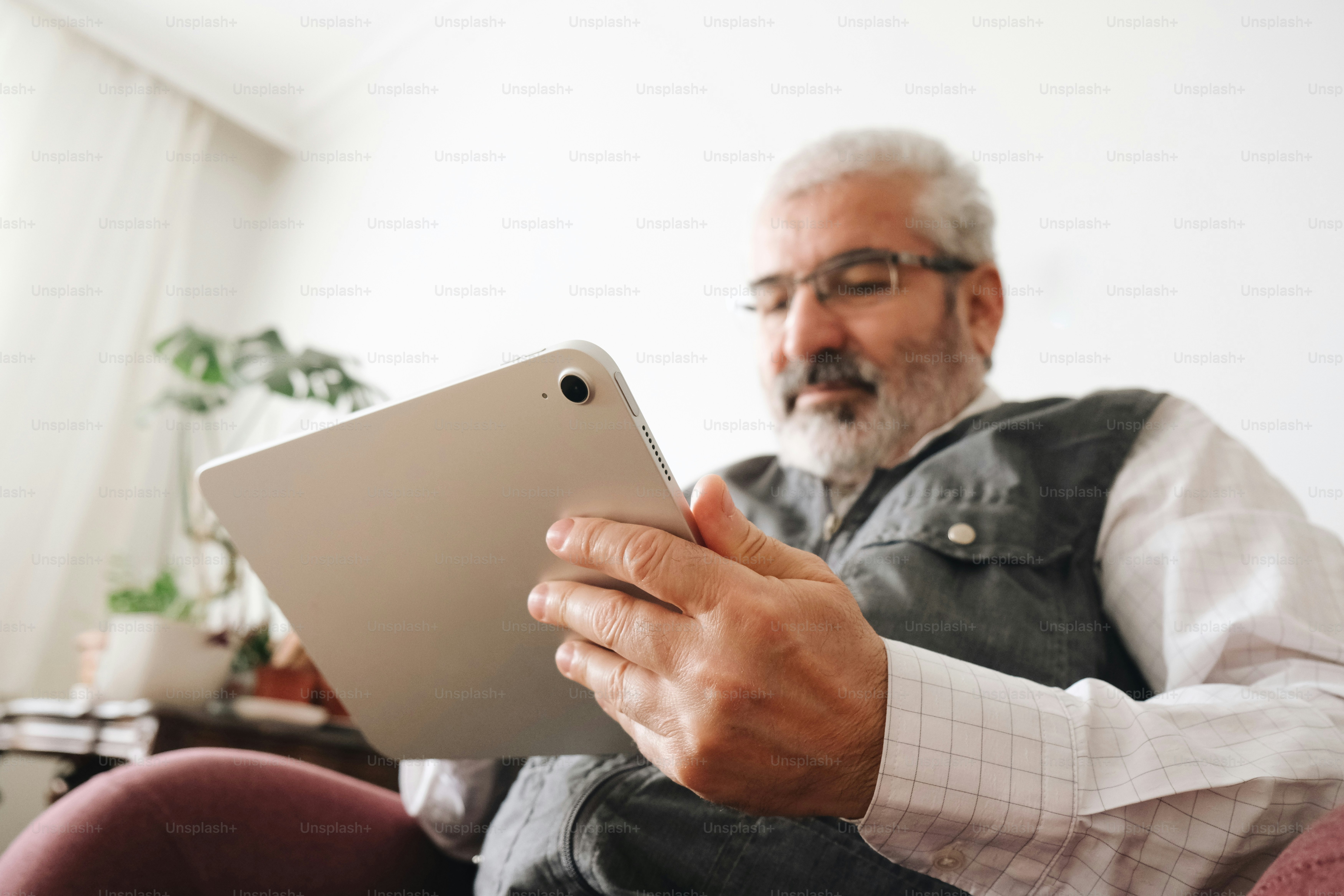 Uomo barbuto con gli occhiali concentrato sullo schermo di un tablet