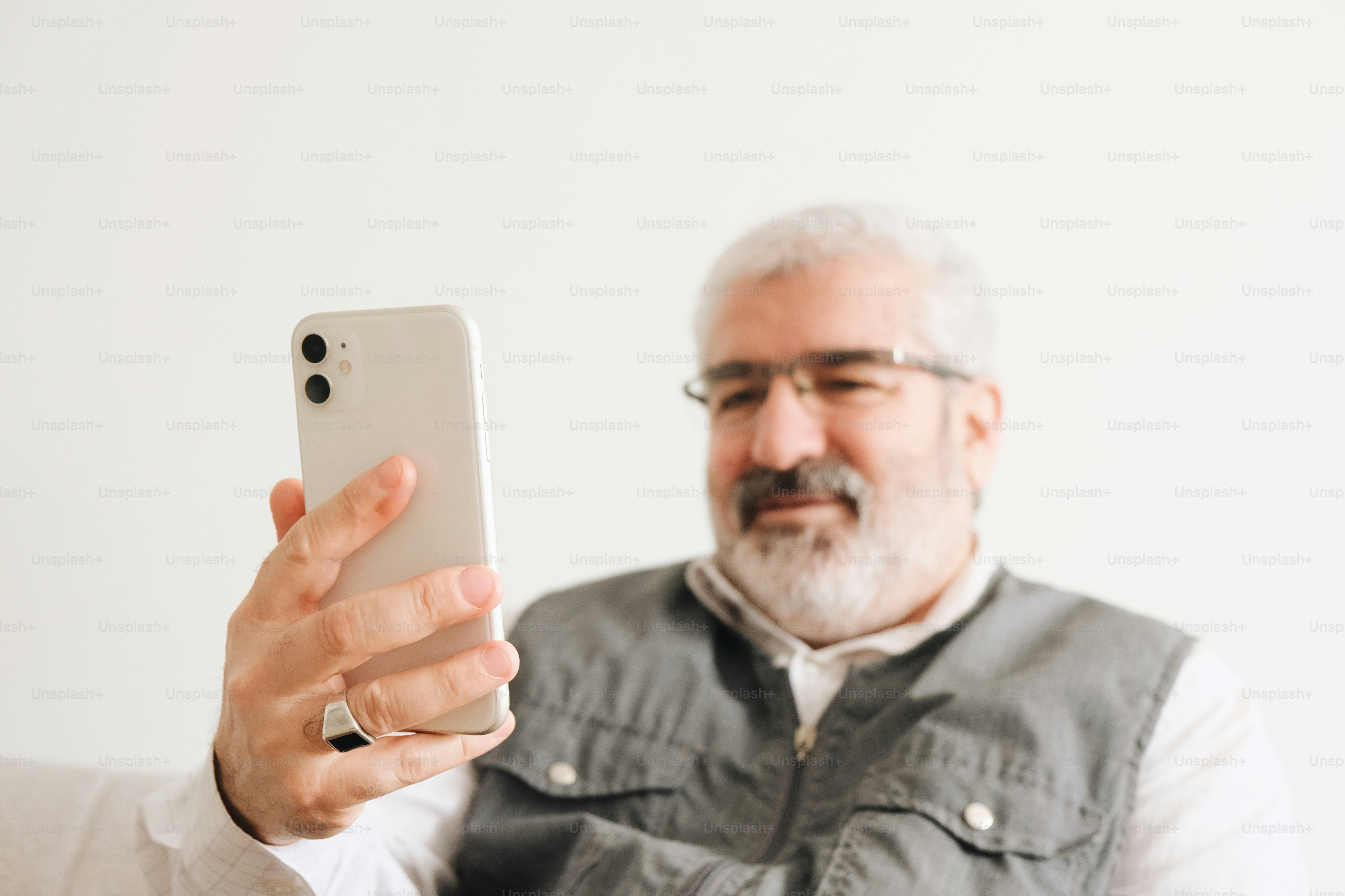 Uomo con la barba e gli occhiali che tiene uno smartphone