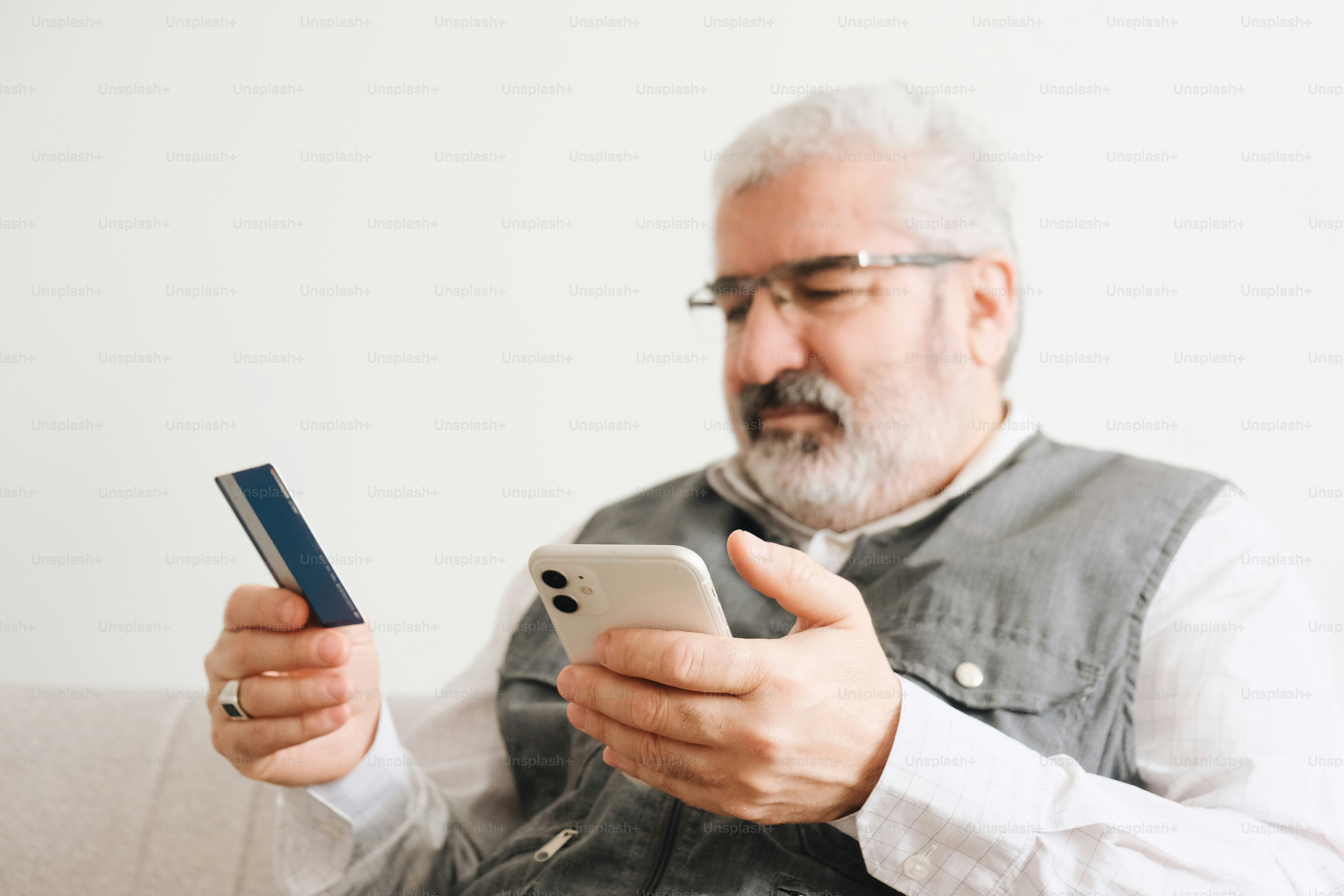 Uomo anziano che possiede carta di credito e smartphone per lo shopping online