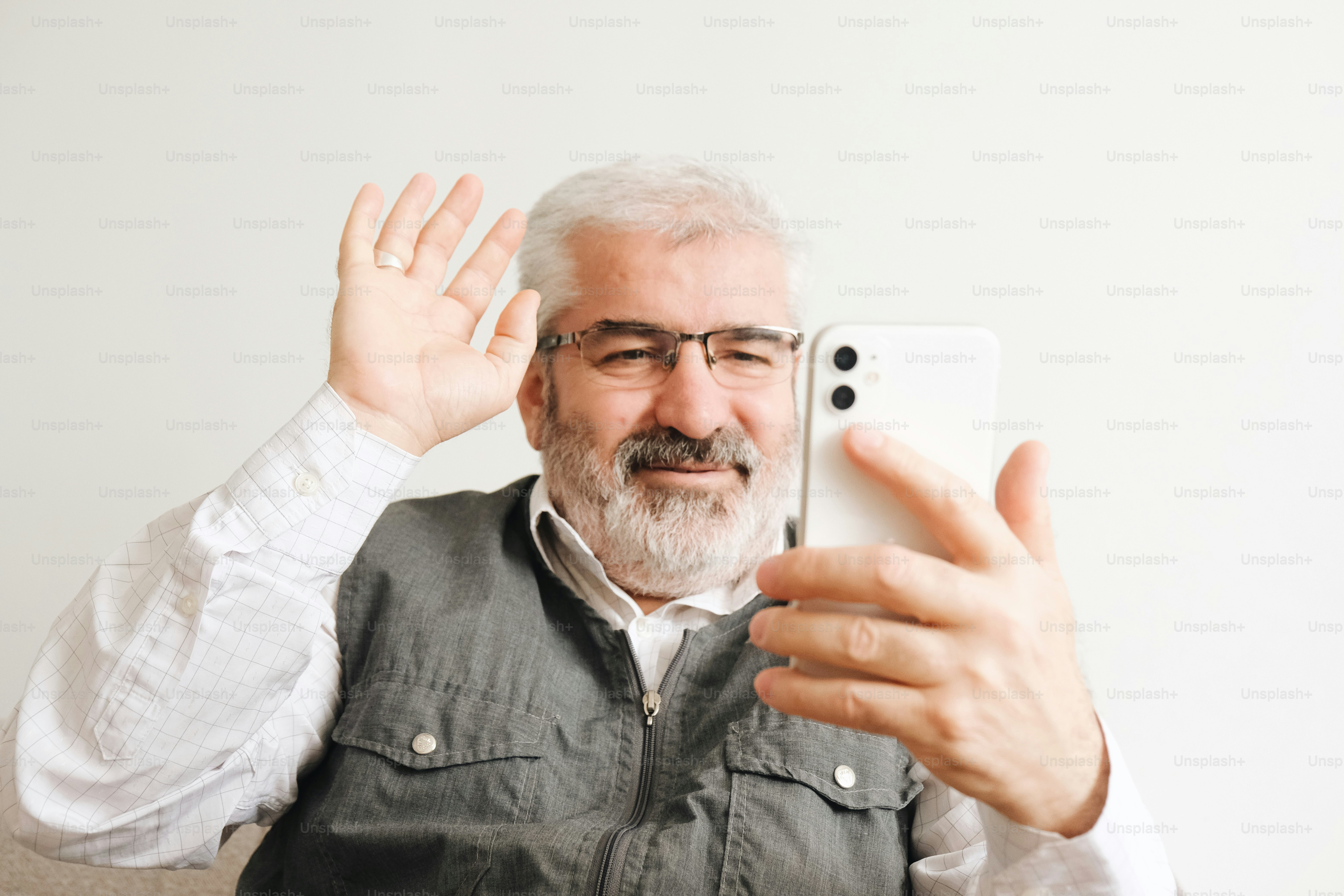 Un uomo saluta mentre si fa un selfie con il suo smartphone
