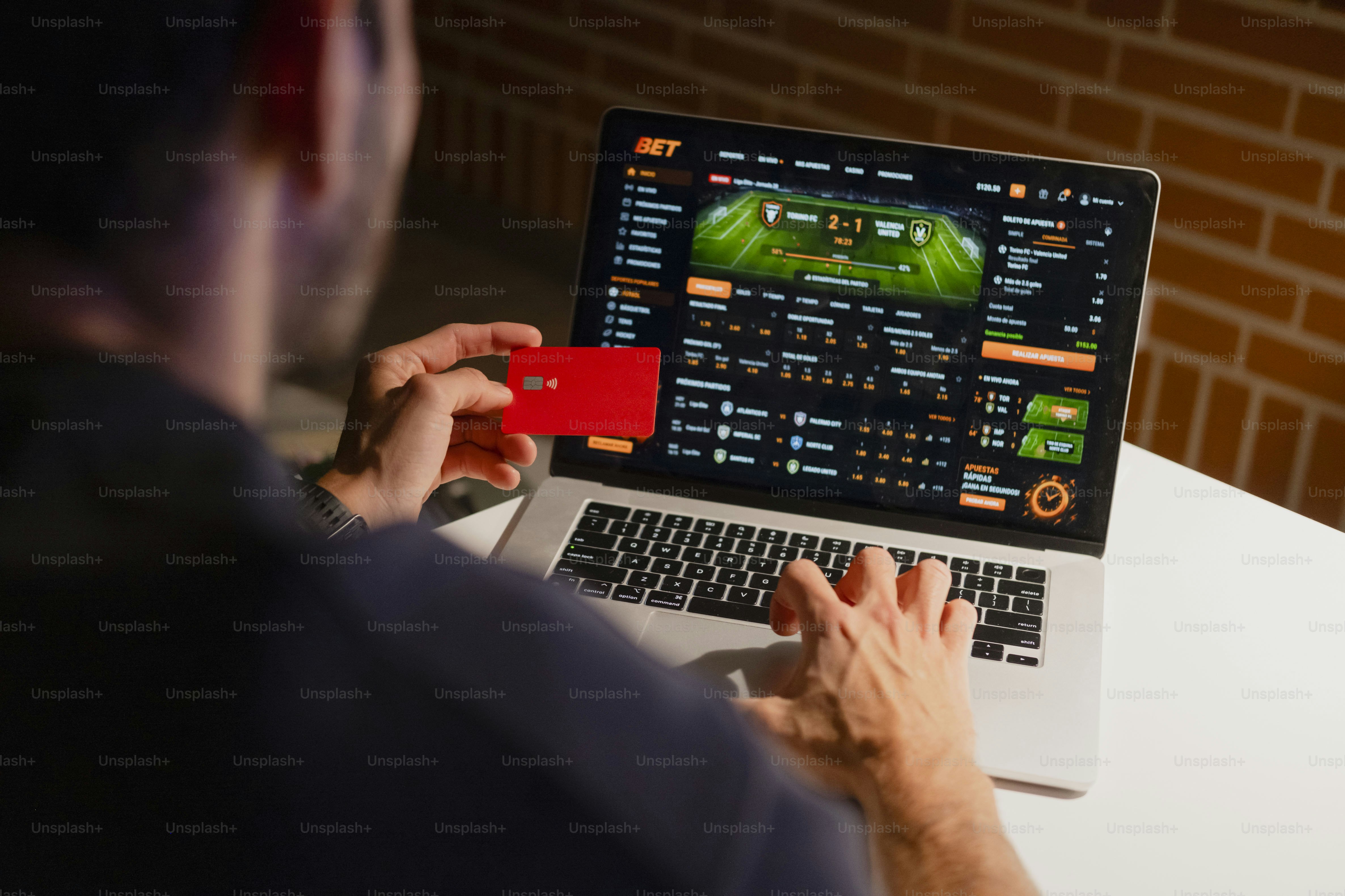 Man using laptop and credit card for online sports betting.