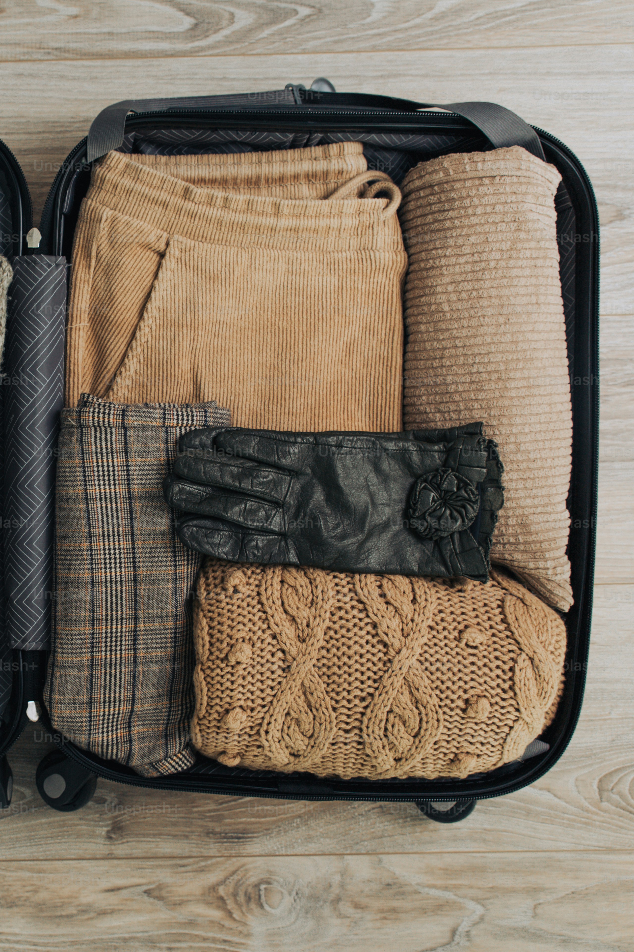 Valise remplie de vêtements marron et gants noirs.