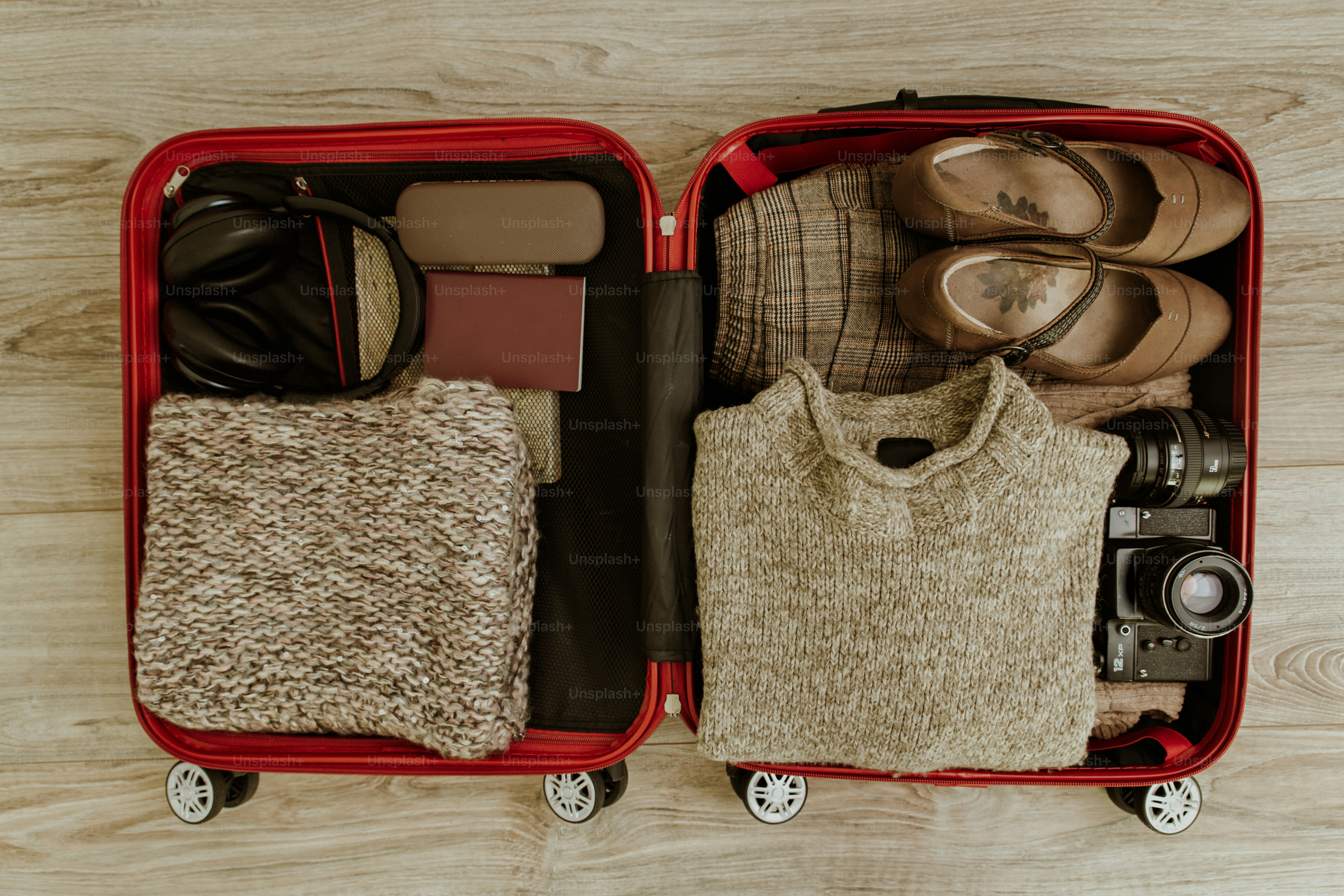 Ouvrez une valise rouge remplie de vêtements, chaussures et articles de voyage.