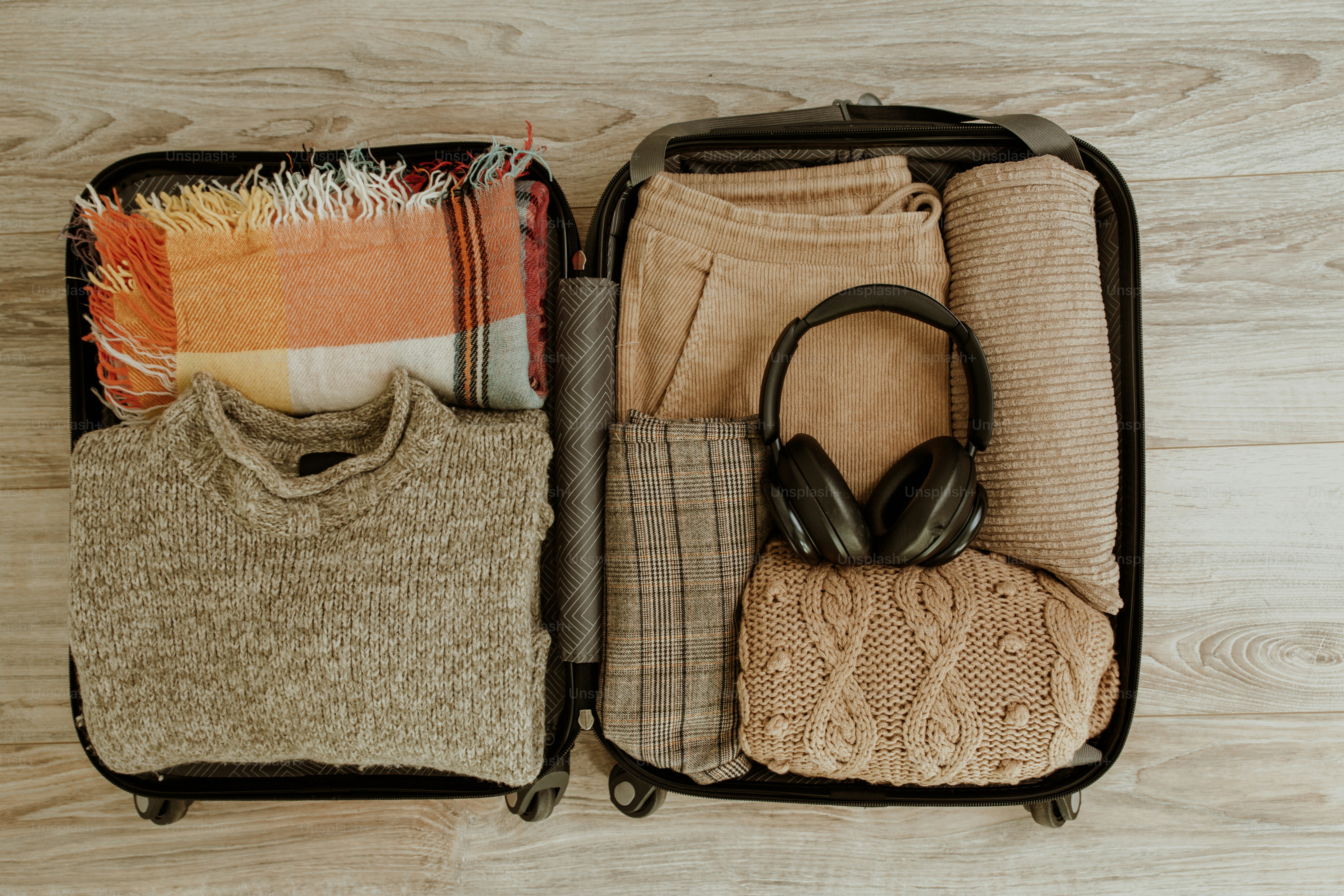 Une valise ouverte remplie de vêtements soigneusement rangés et de casques.