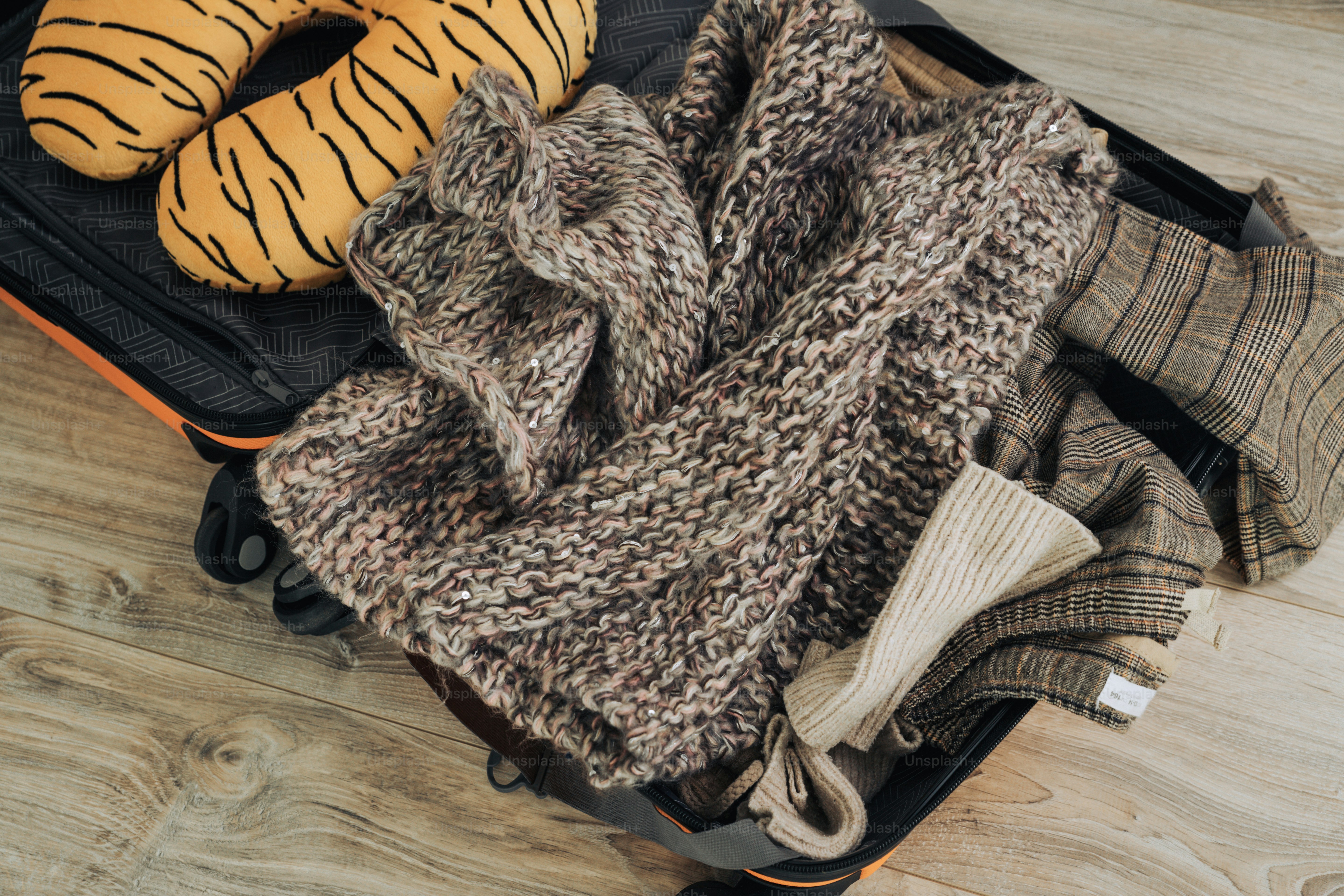 Valise remplie de vêtements et un oreiller de voyage rayé de tigre.