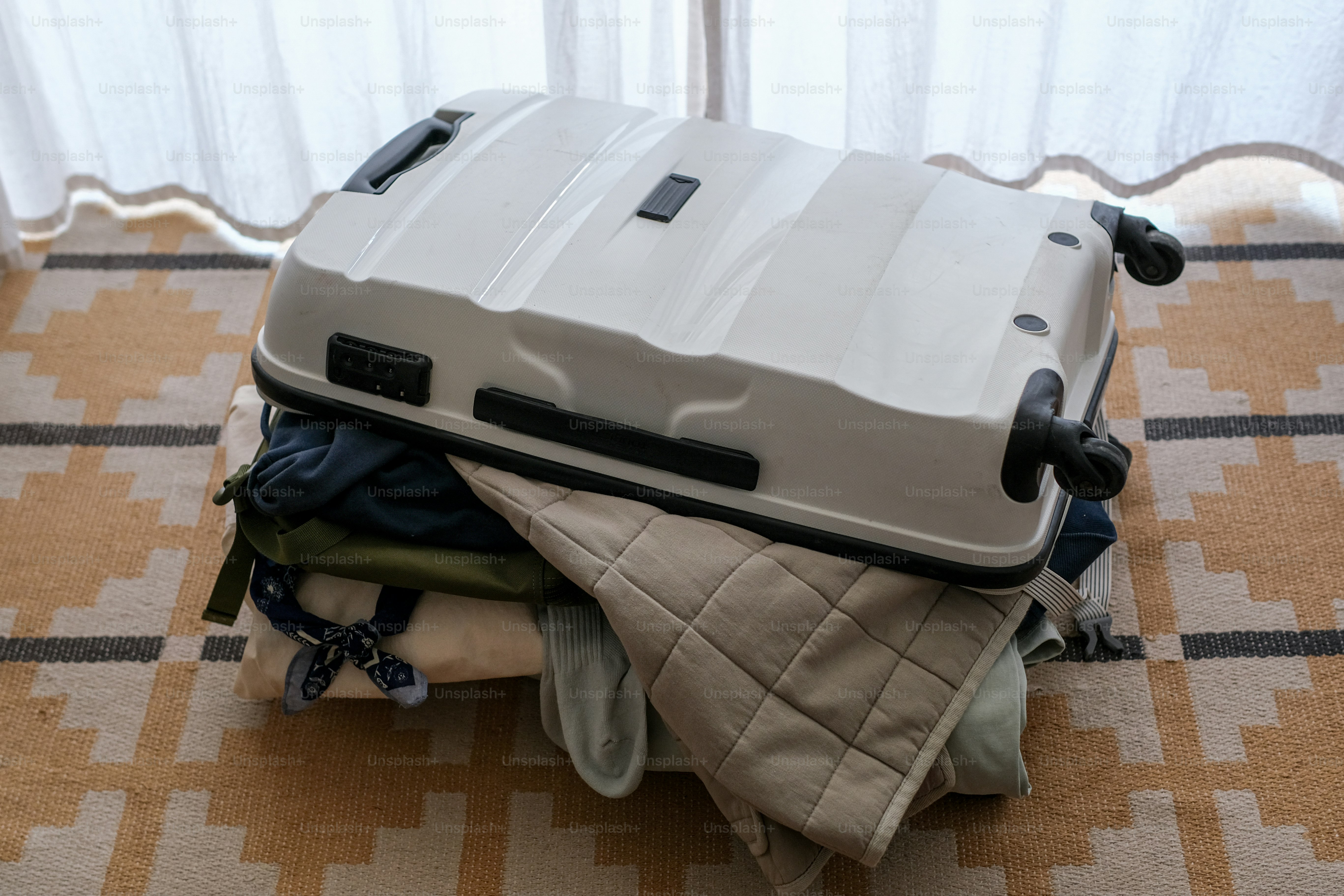 A white suitcase on a pile of clothes.