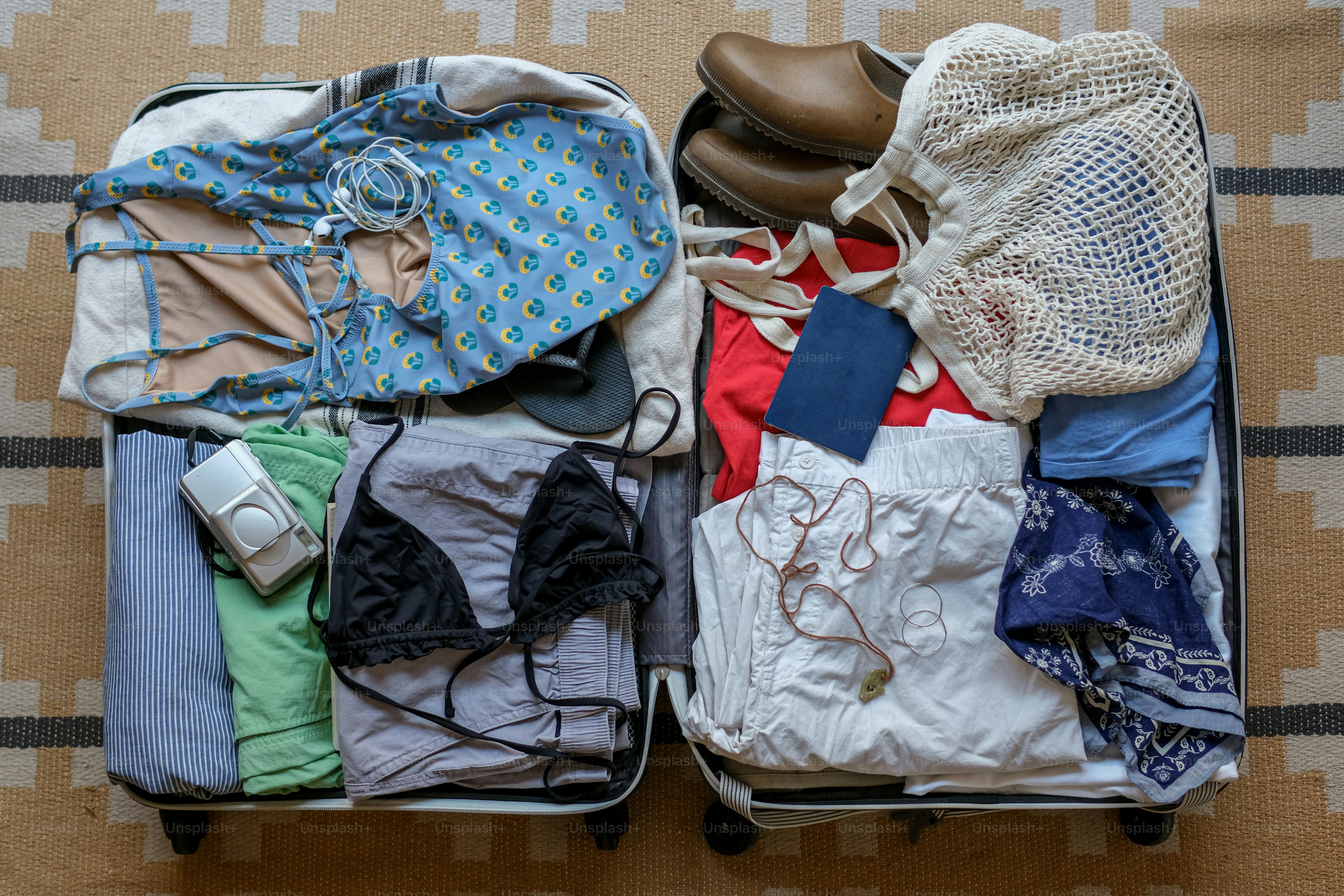 An open suitcase packed with clothes, shoes, and accessories.