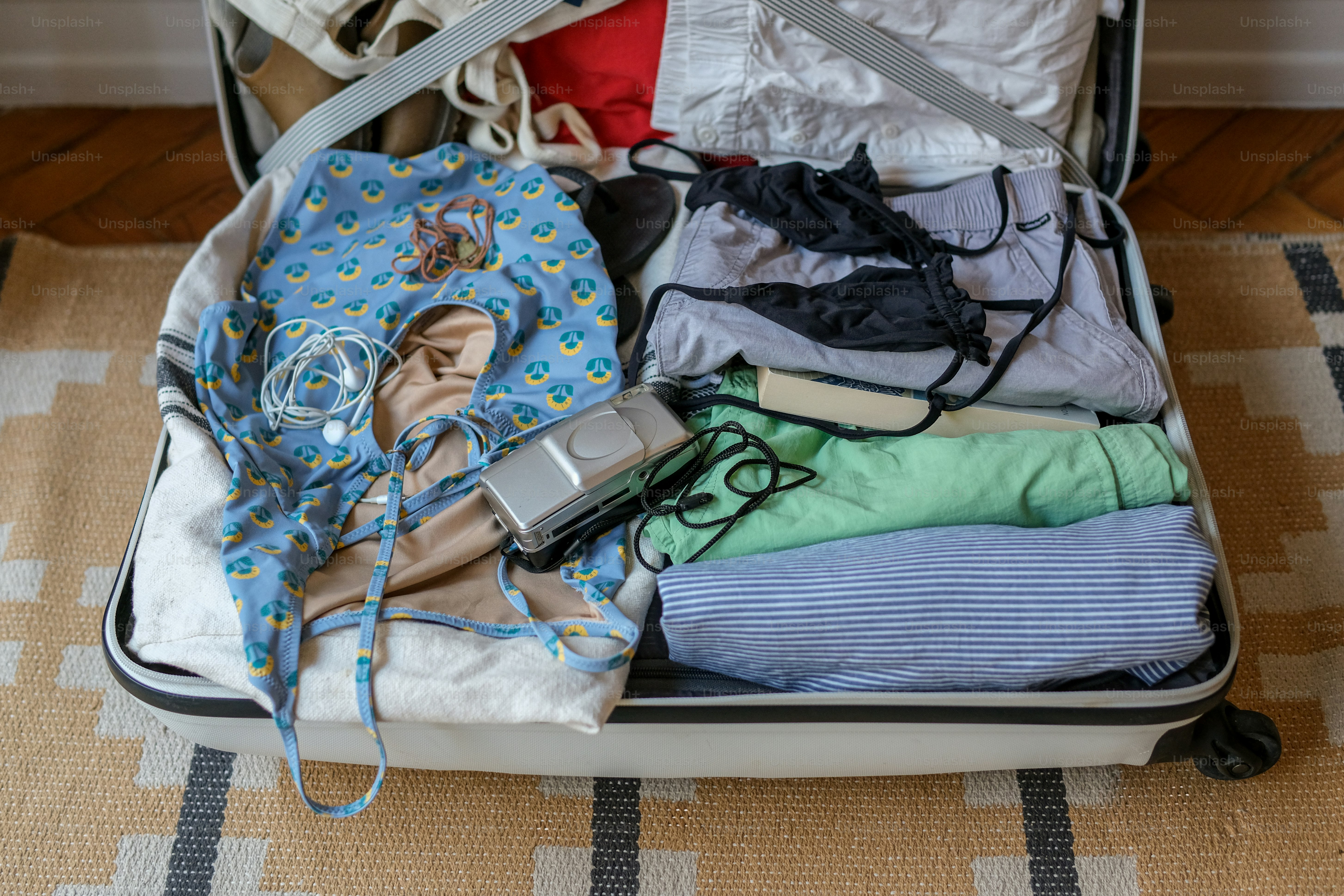 An open suitcase packed with various clothes and travel essentials.