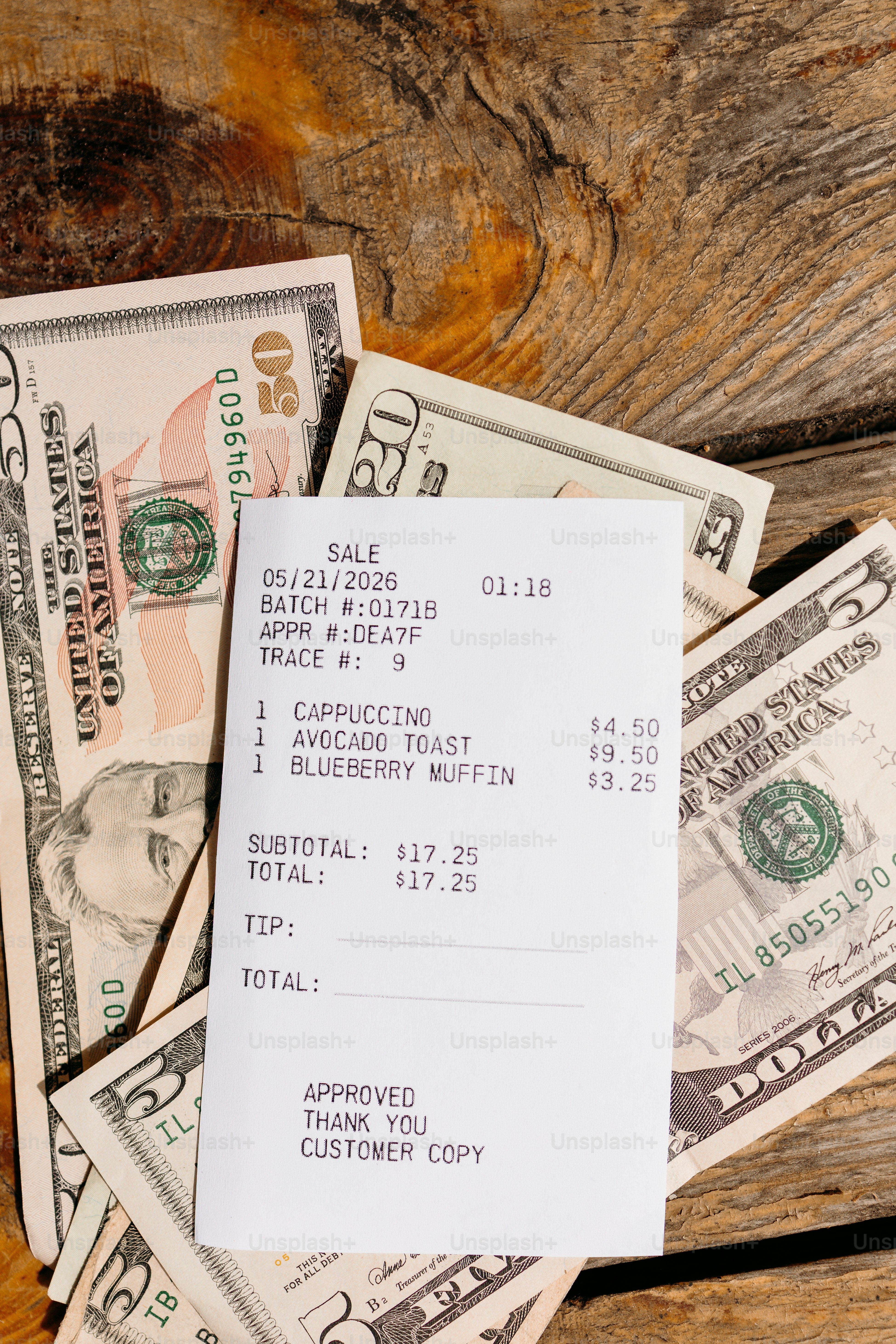 Tanda terima kedai kopi dengan uang dolar di atas kayu pedesaan.
