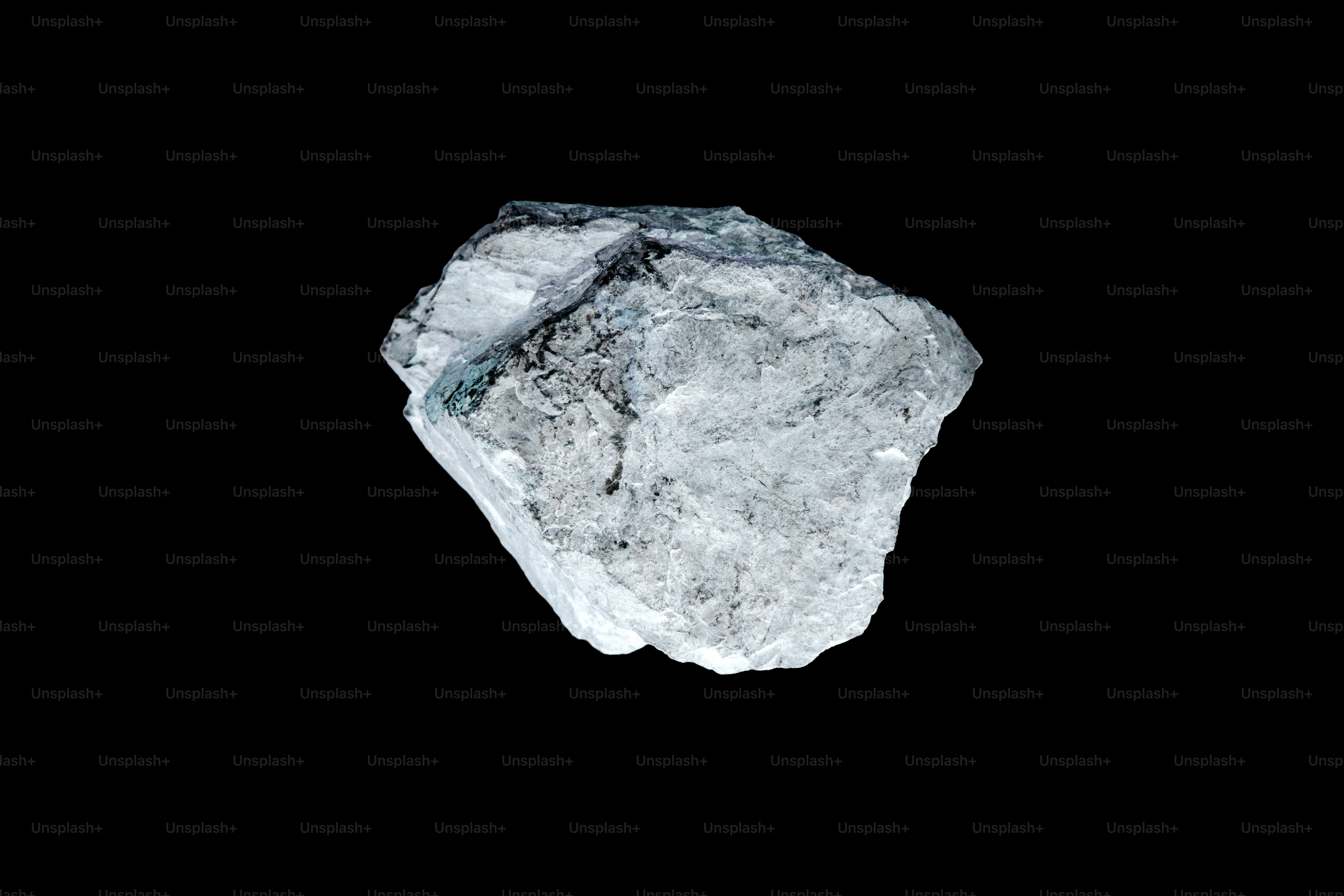 Una roccia grigio chiaro ruvida su uno sfondo nero.