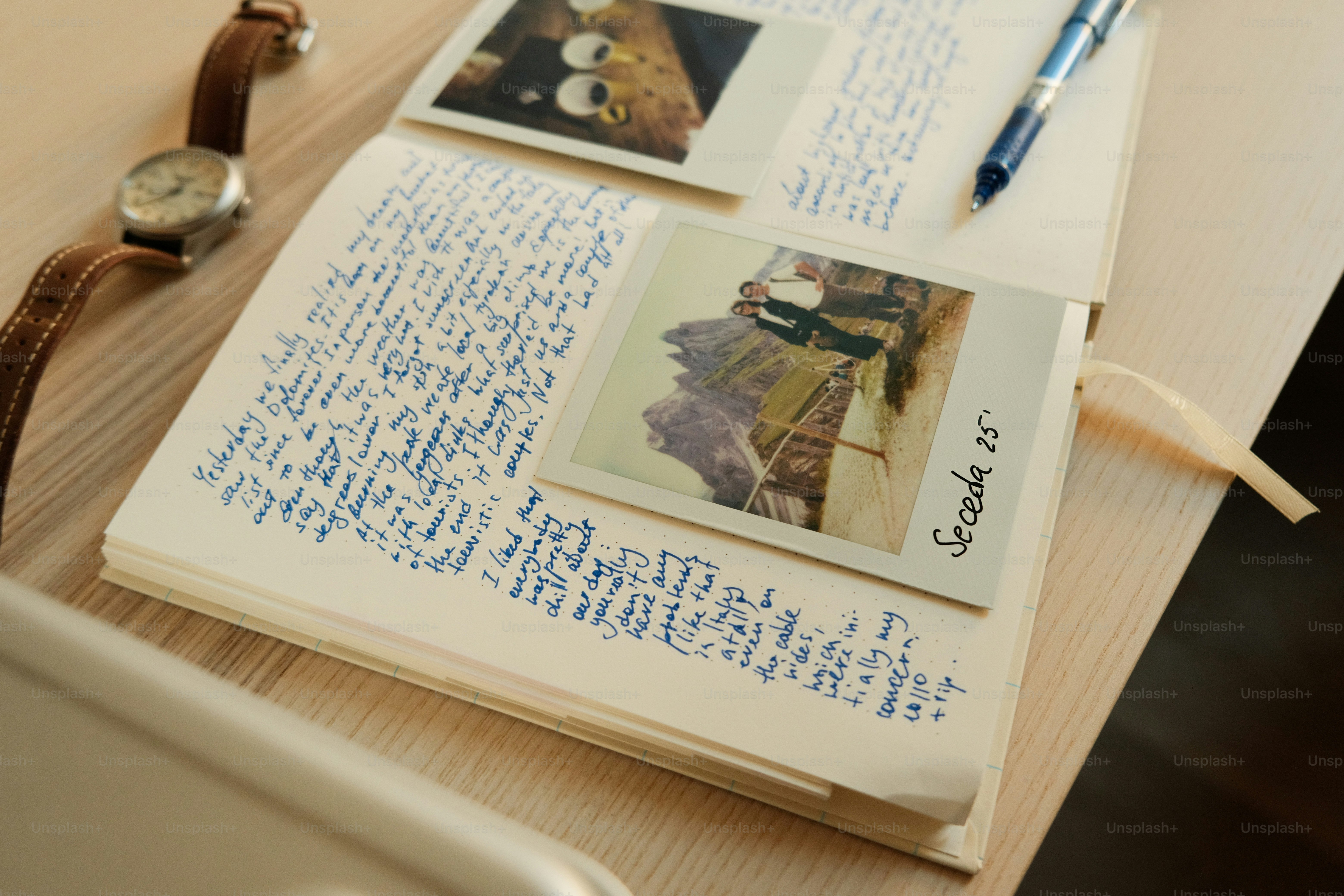手書きのジャーナルにインスタント写真、ペン、腕時計が添付されています。