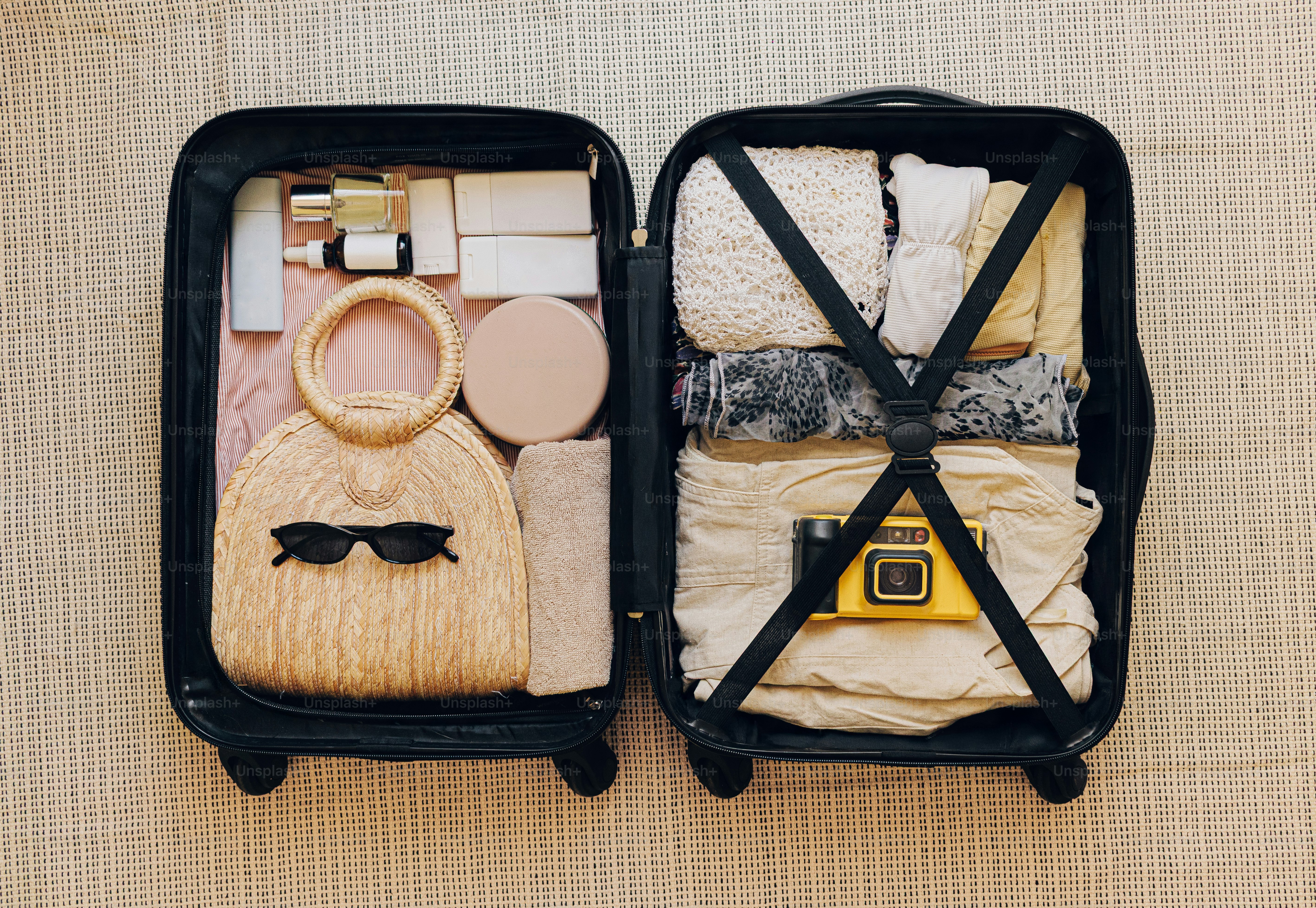 服や化粧品、黄色いカメラが詰まった旅行用スーツケース。