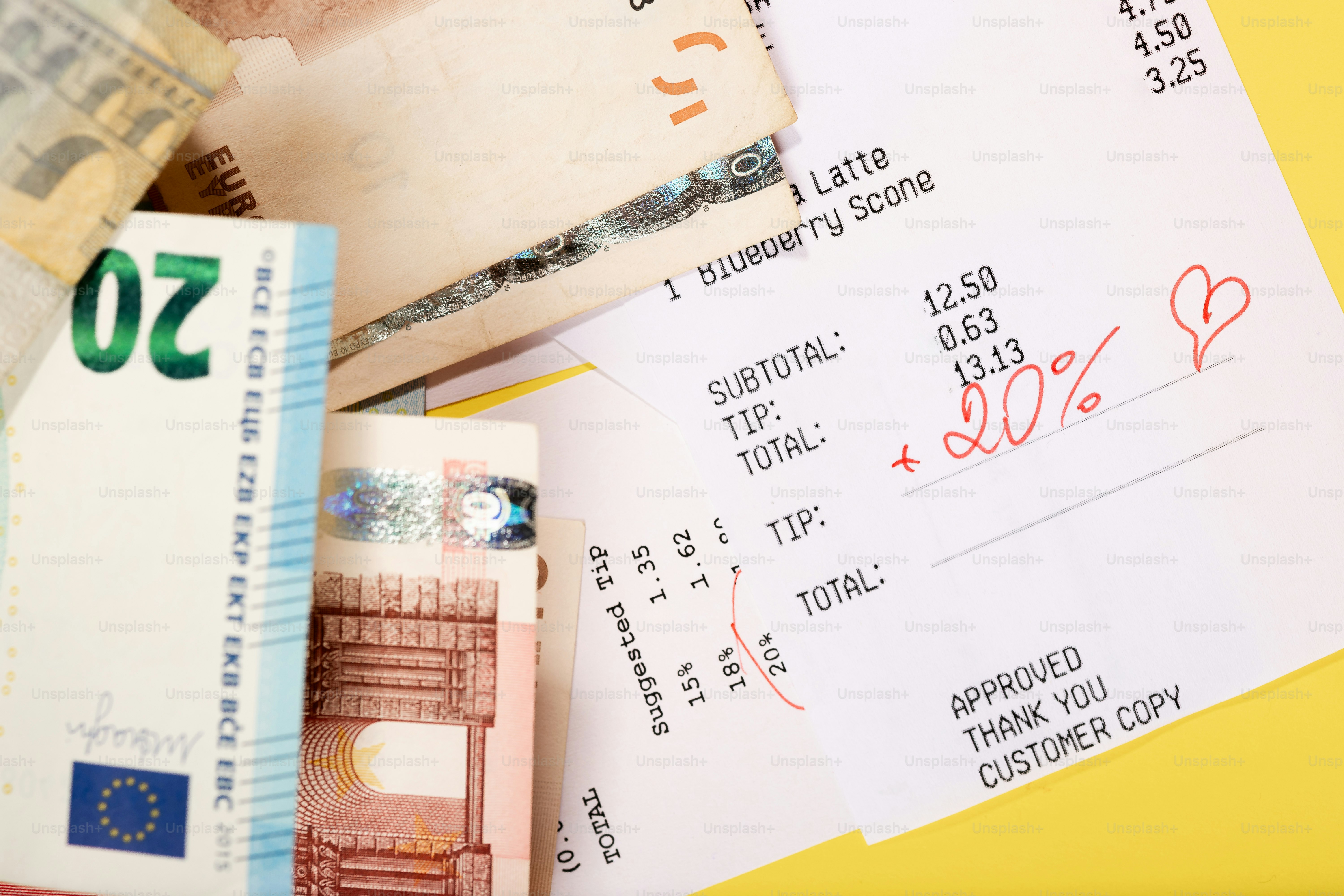 Tagihan restoran dengan tip 20% dan uang kertas euro.