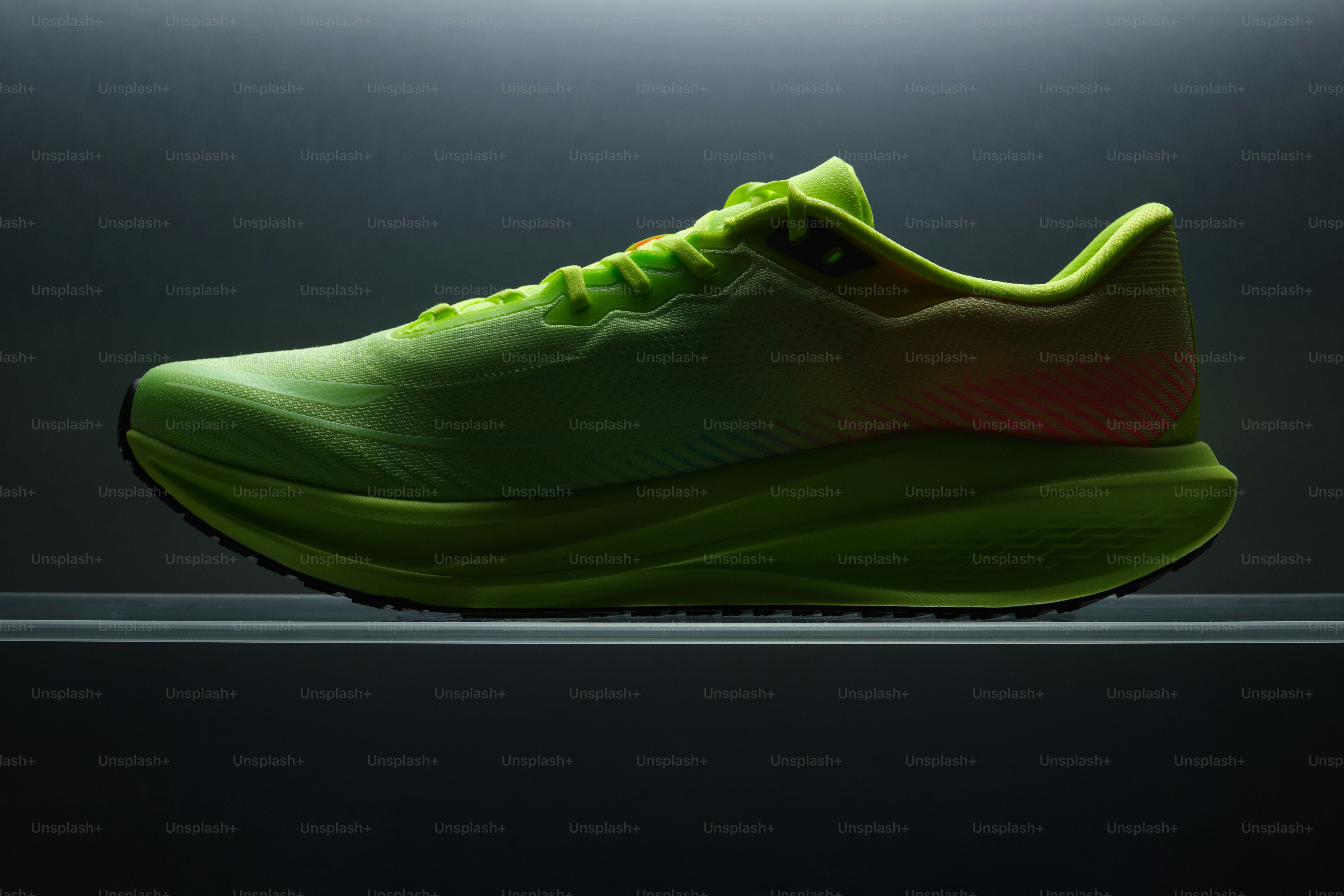 Chaussures de course vert vif avec talon rose sur fond foncé.