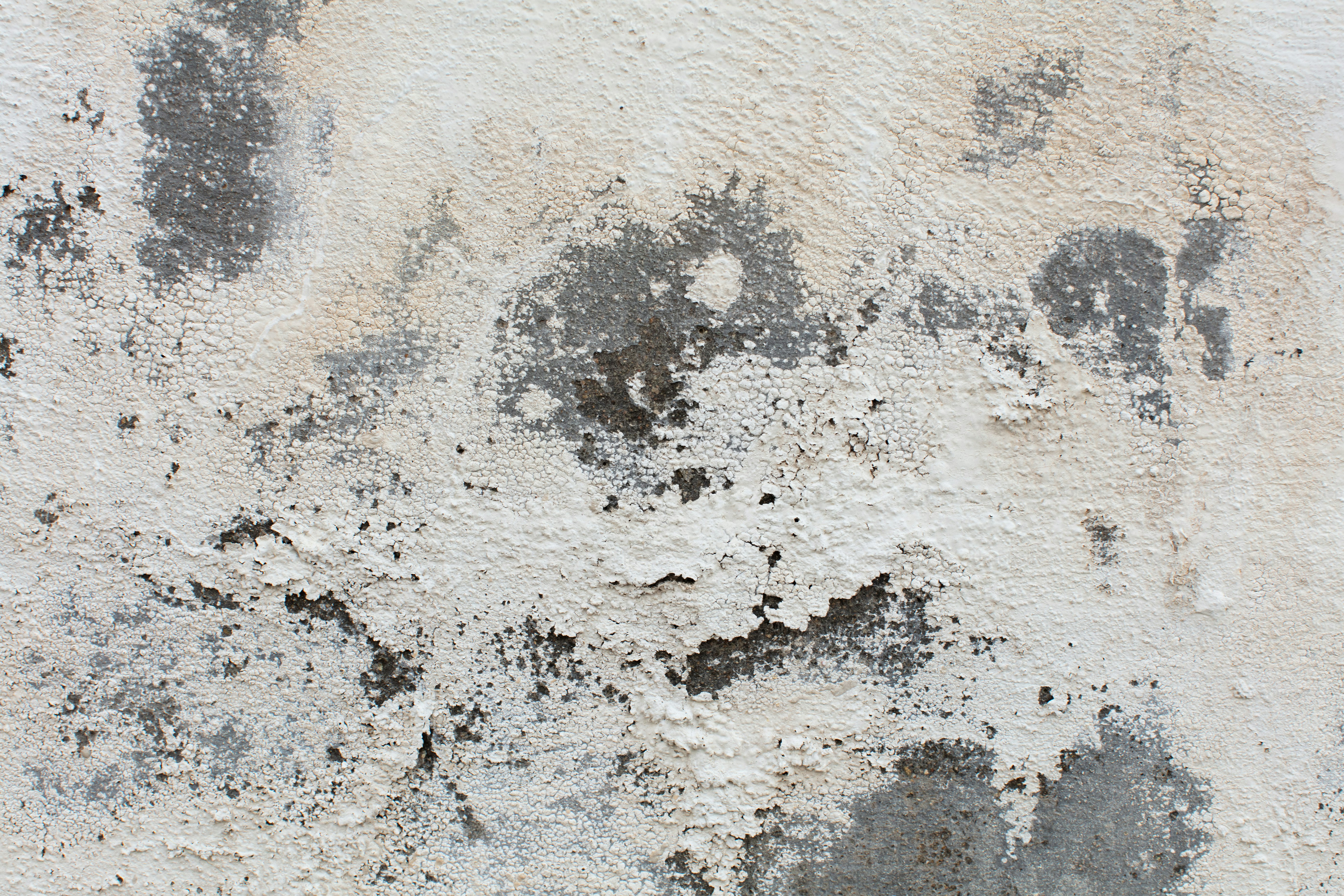 Peeling white paint shows damage and decay on a weathered old concrete wall texture