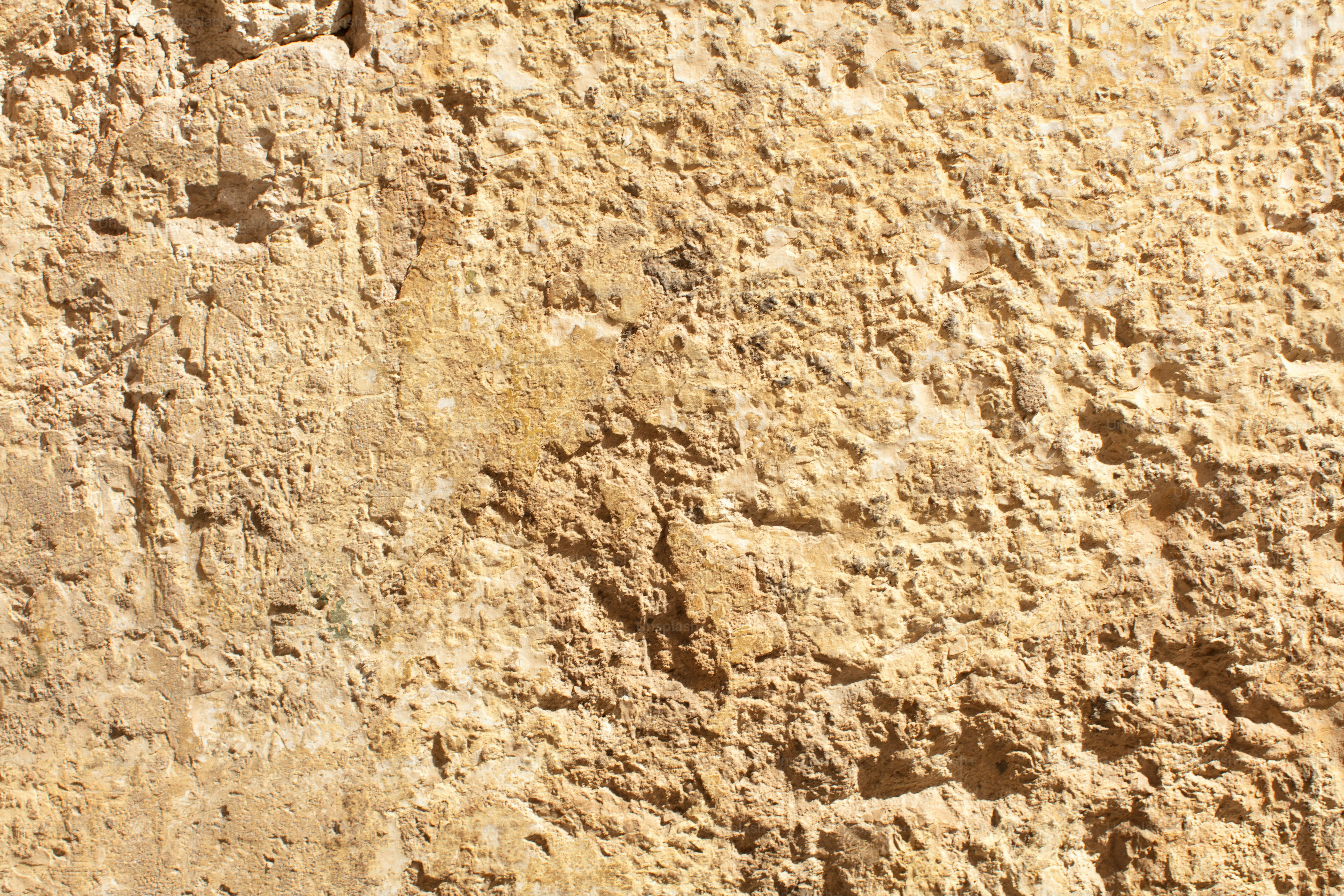 Rough, textured light brown stone surface with natural imperfections