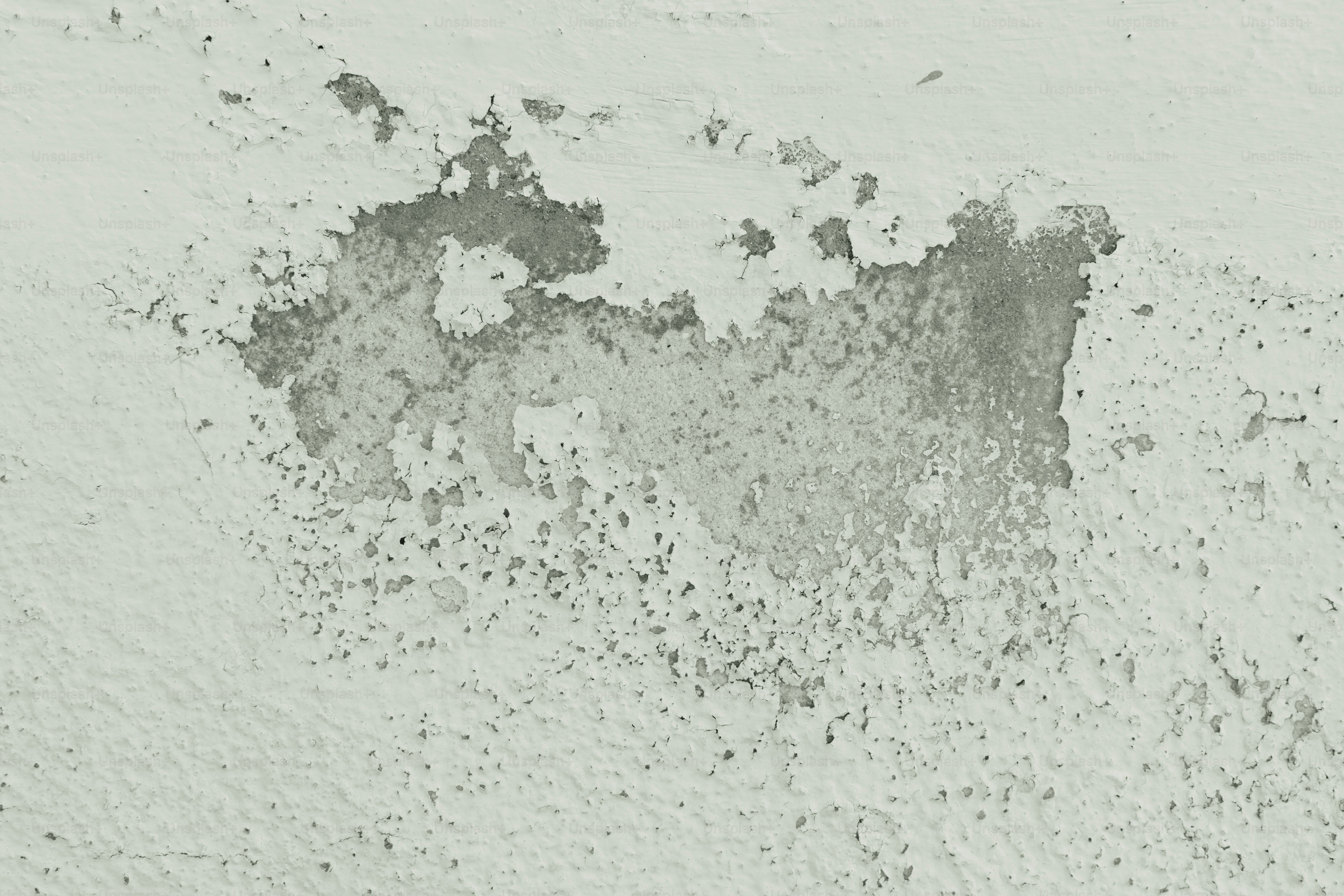 Peeling white paint deteriorating from an old concrete wall texture