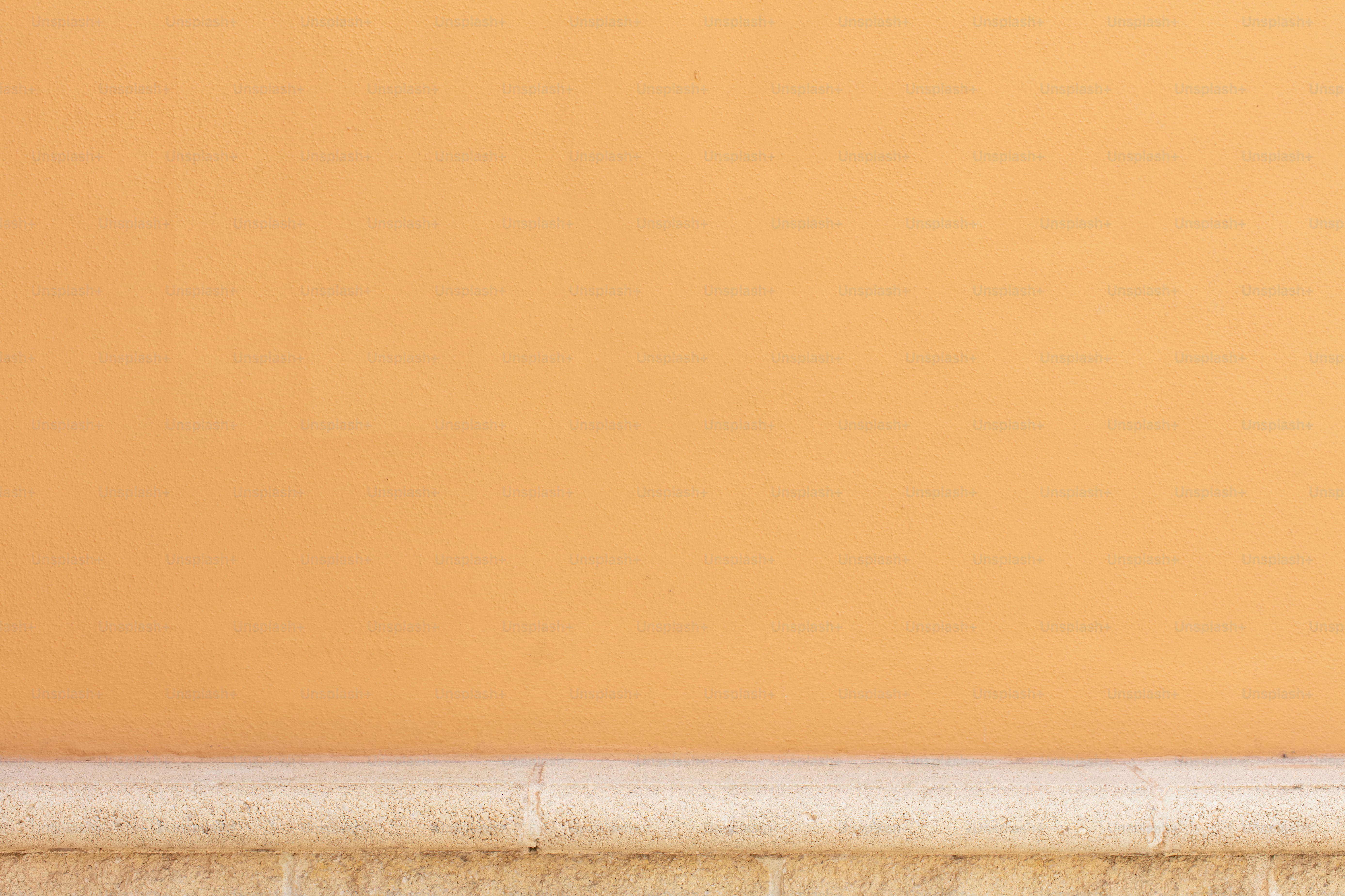 Un mur orange uni avec une plinthe claire