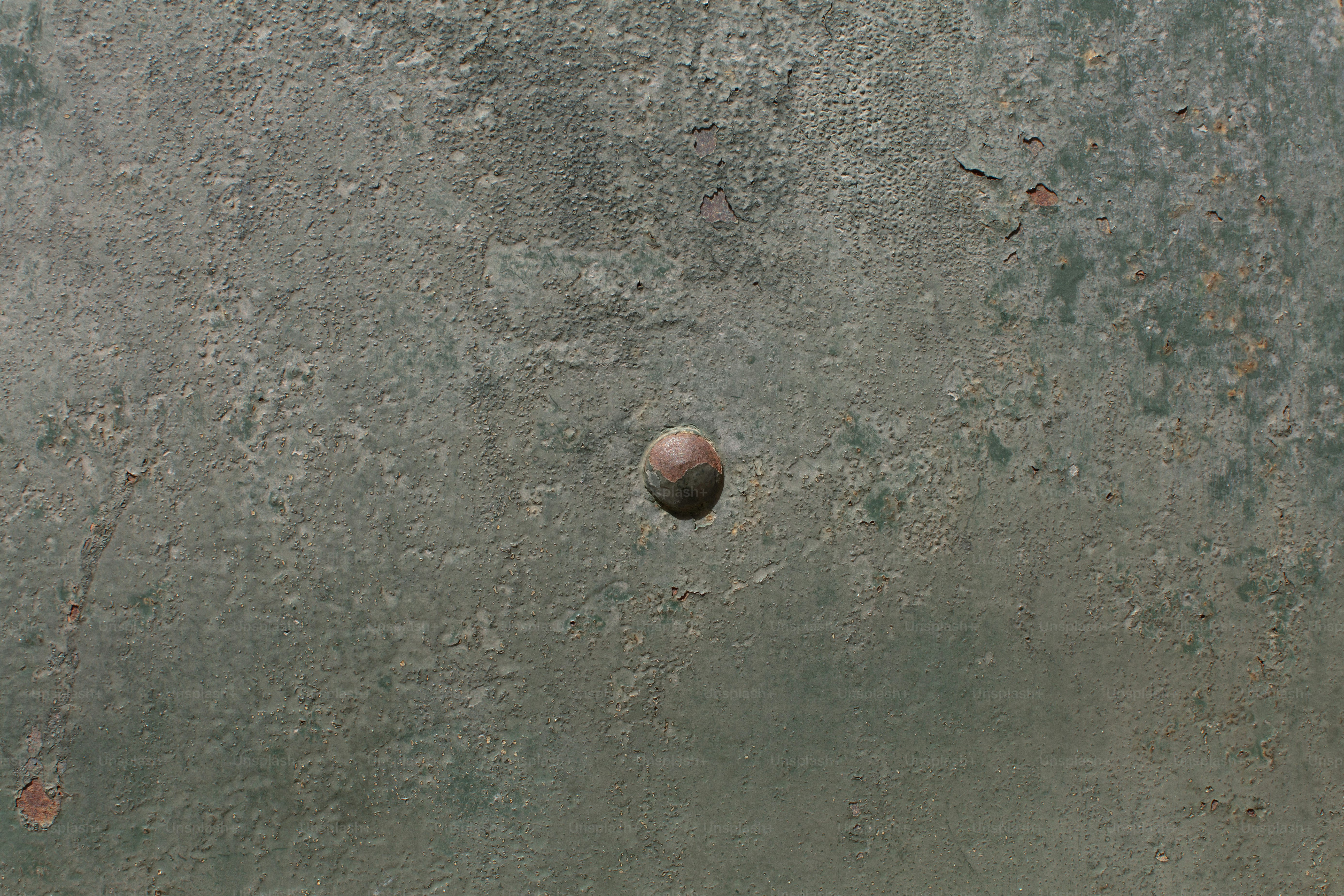 Une surface texturée vert-gris avec un rivet central