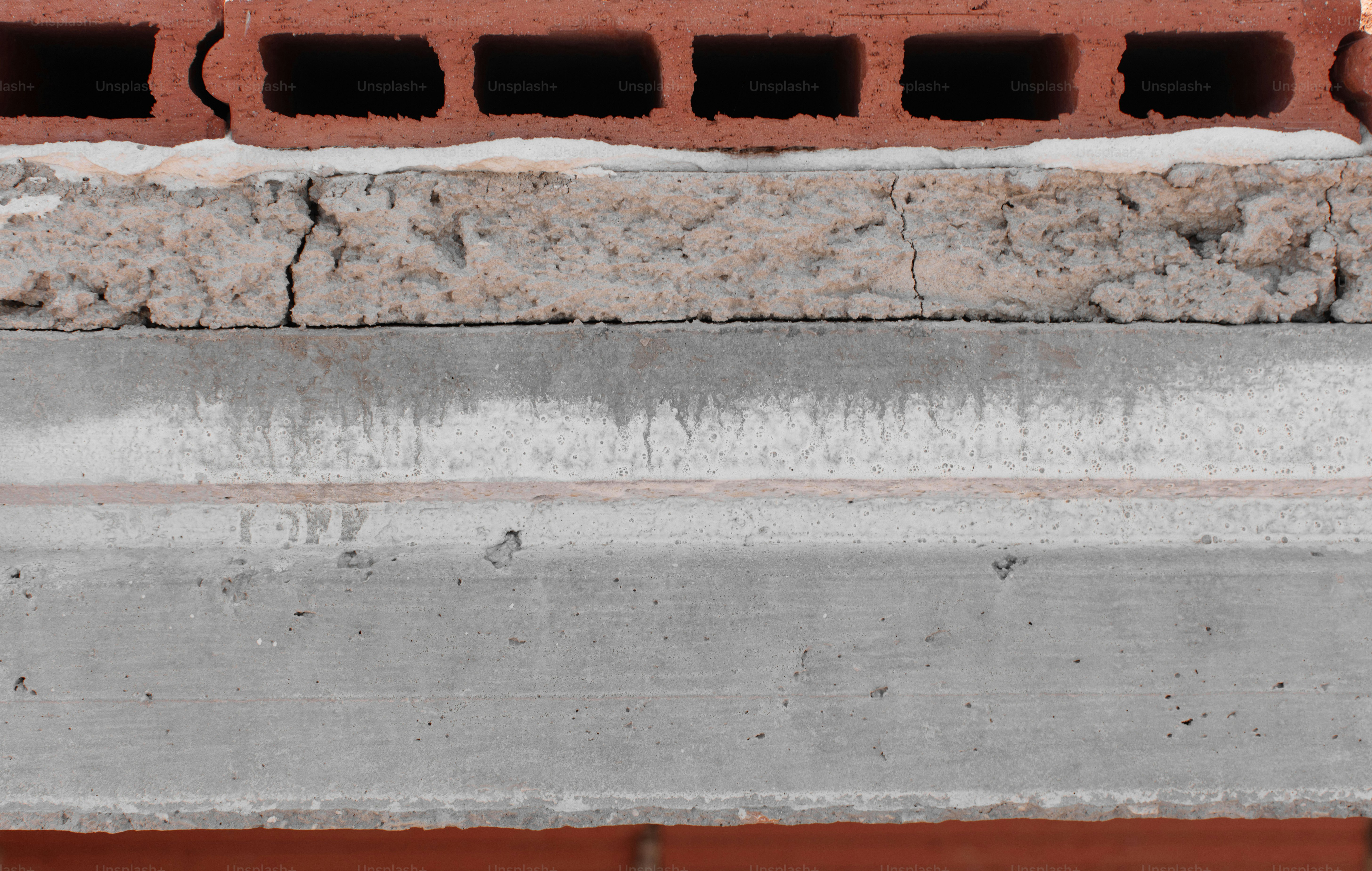 Building cross section exposing hollow bricks, cracked concrete insulation, and a solid concrete beam