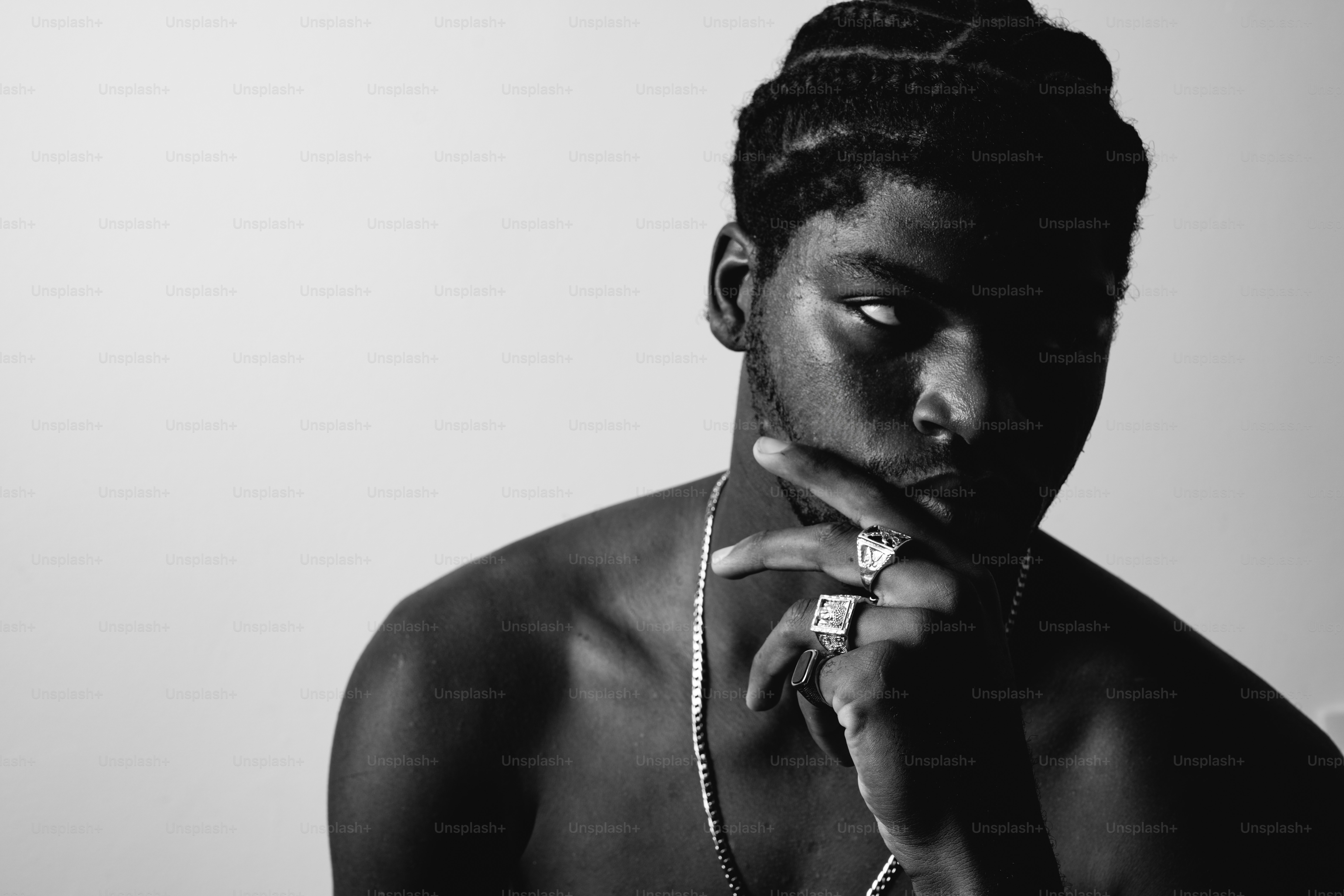 Young man with braids and rings, strong shadows.