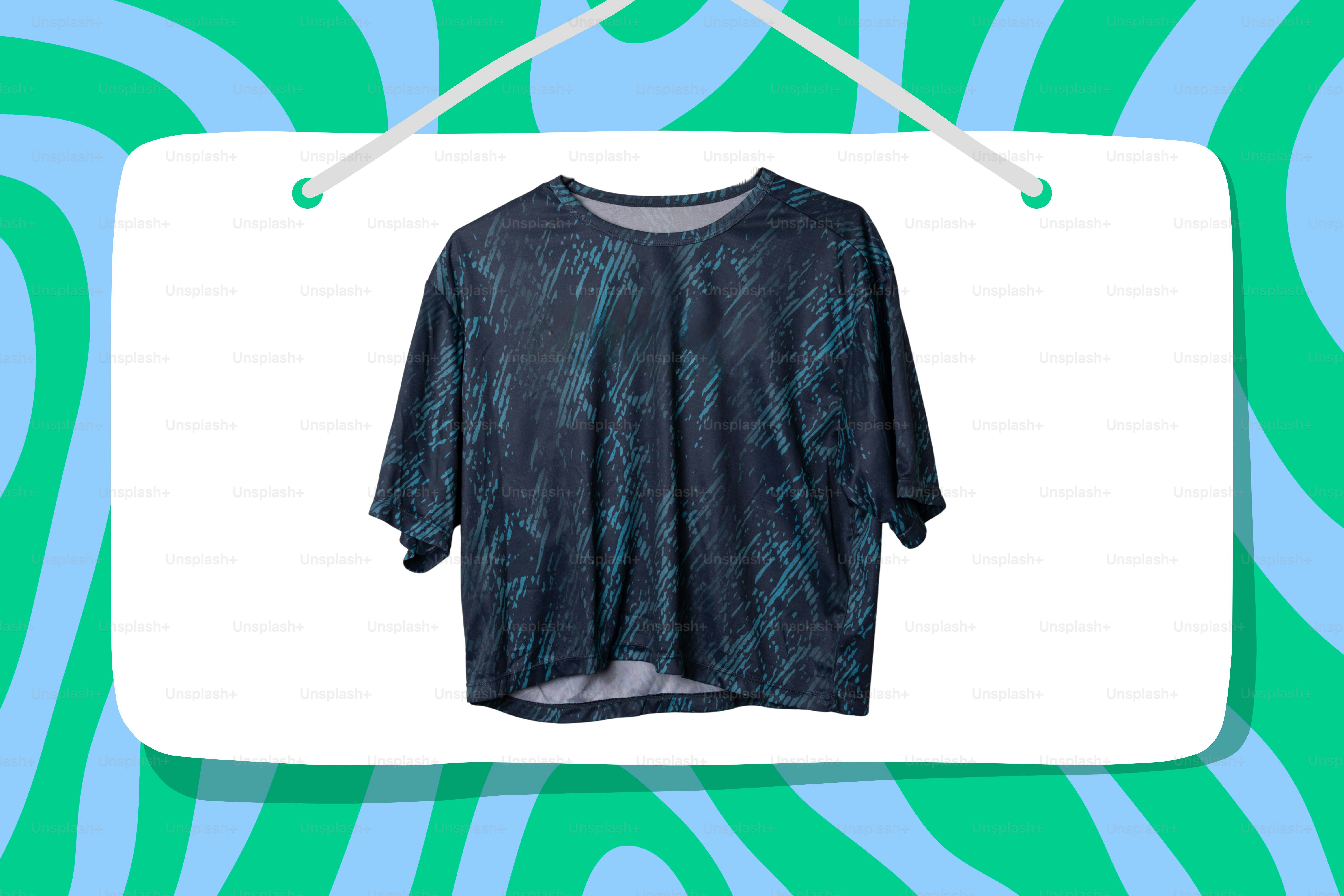 T-shirt bermotif biru tua tergantung di latar belakang bergelombang.