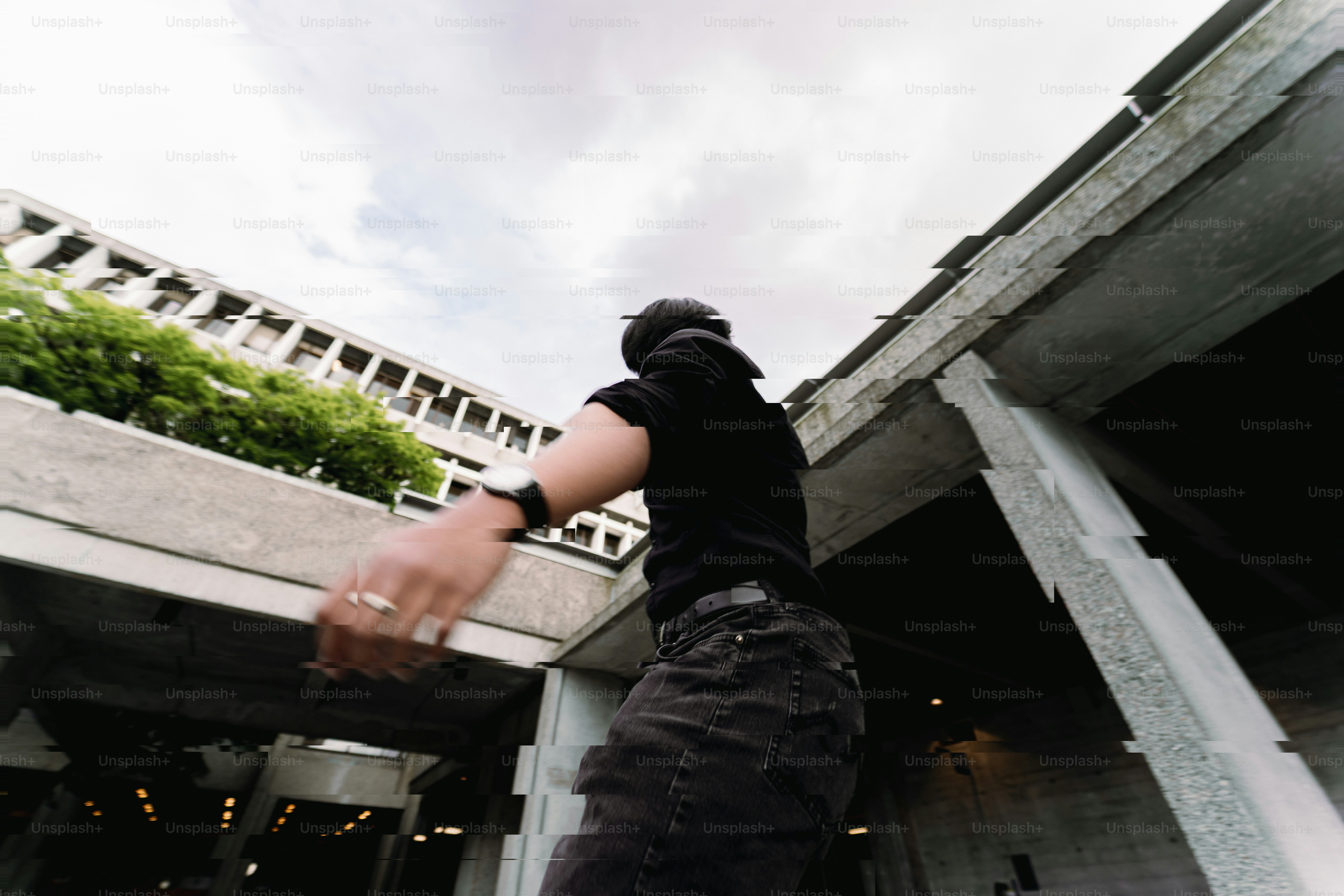 Seseorang berpakaian gelap melompati struktur beton perkotaan.