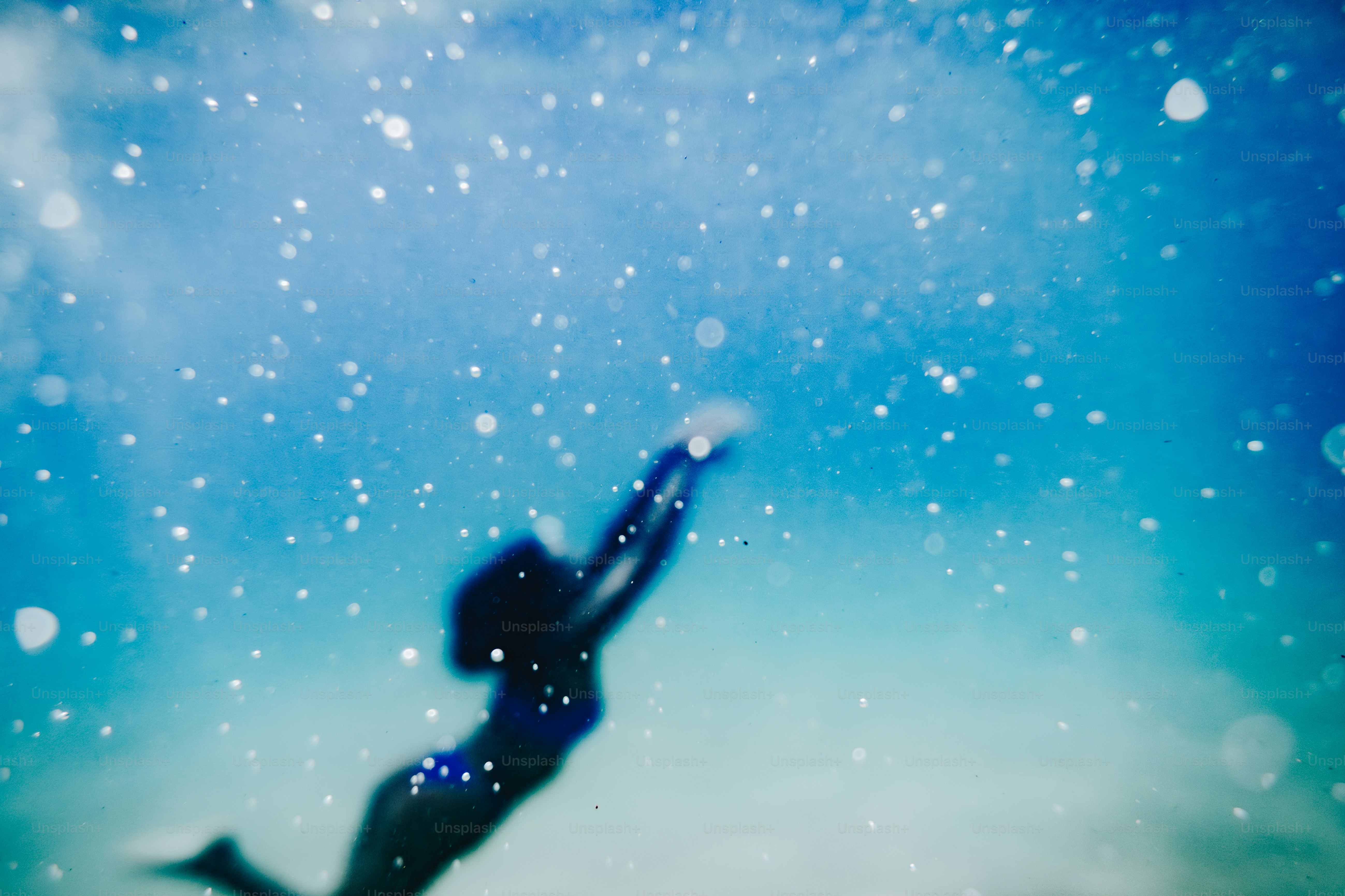 Blurred person swimming in sparkling blue water.