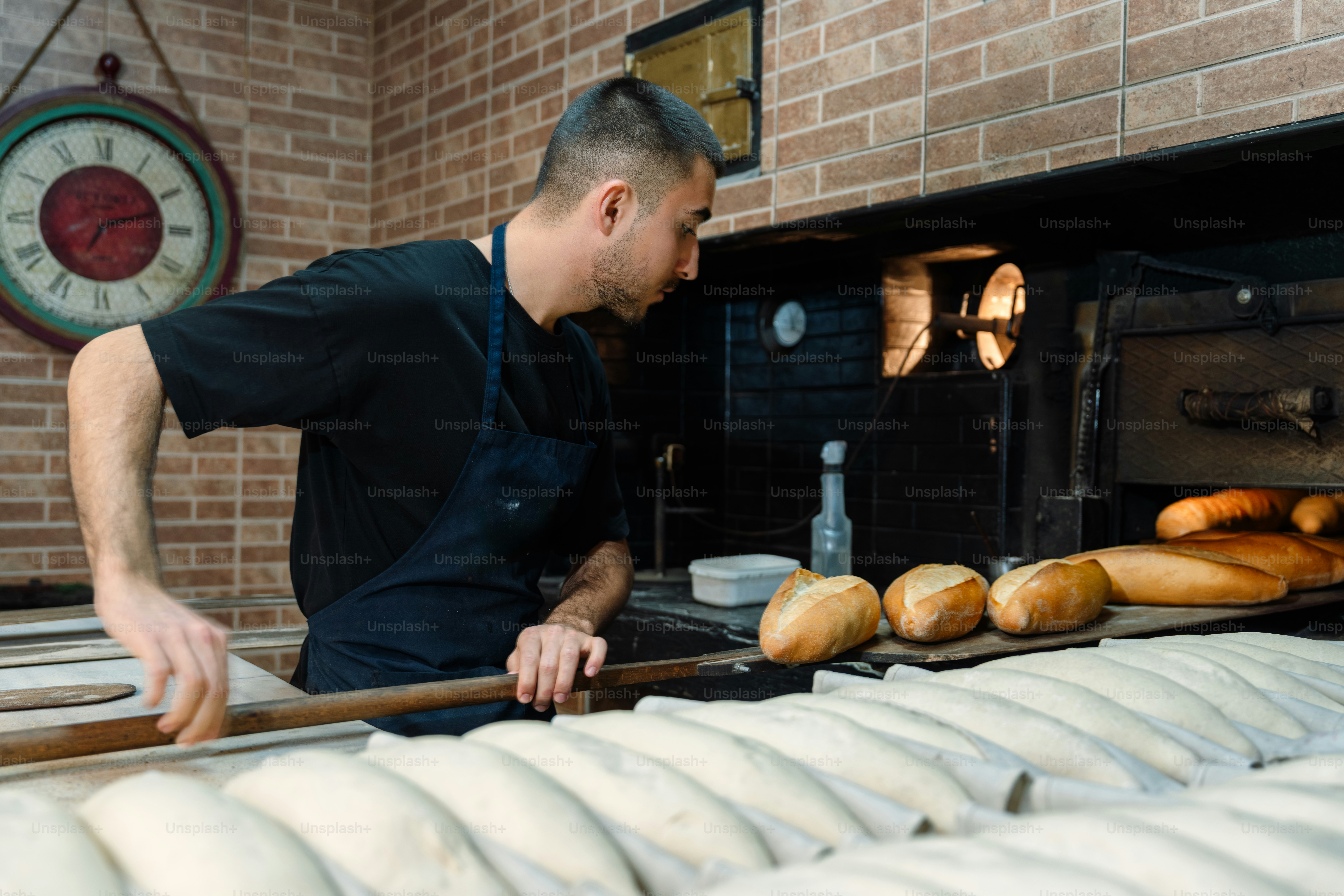 A baker puts fresh bread into a traditional brick oven.