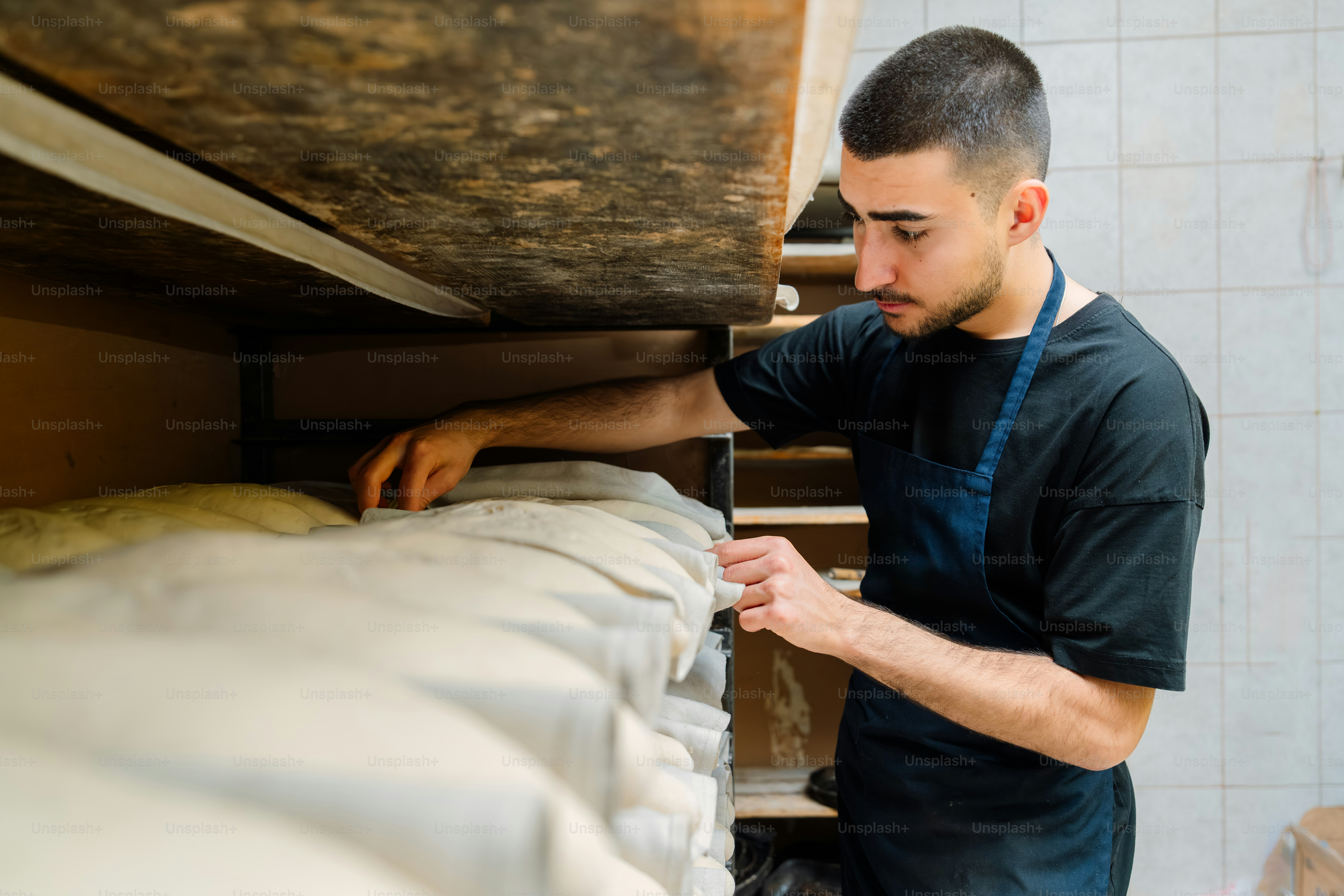 Man in apron arranging bags of flour on a shelf.