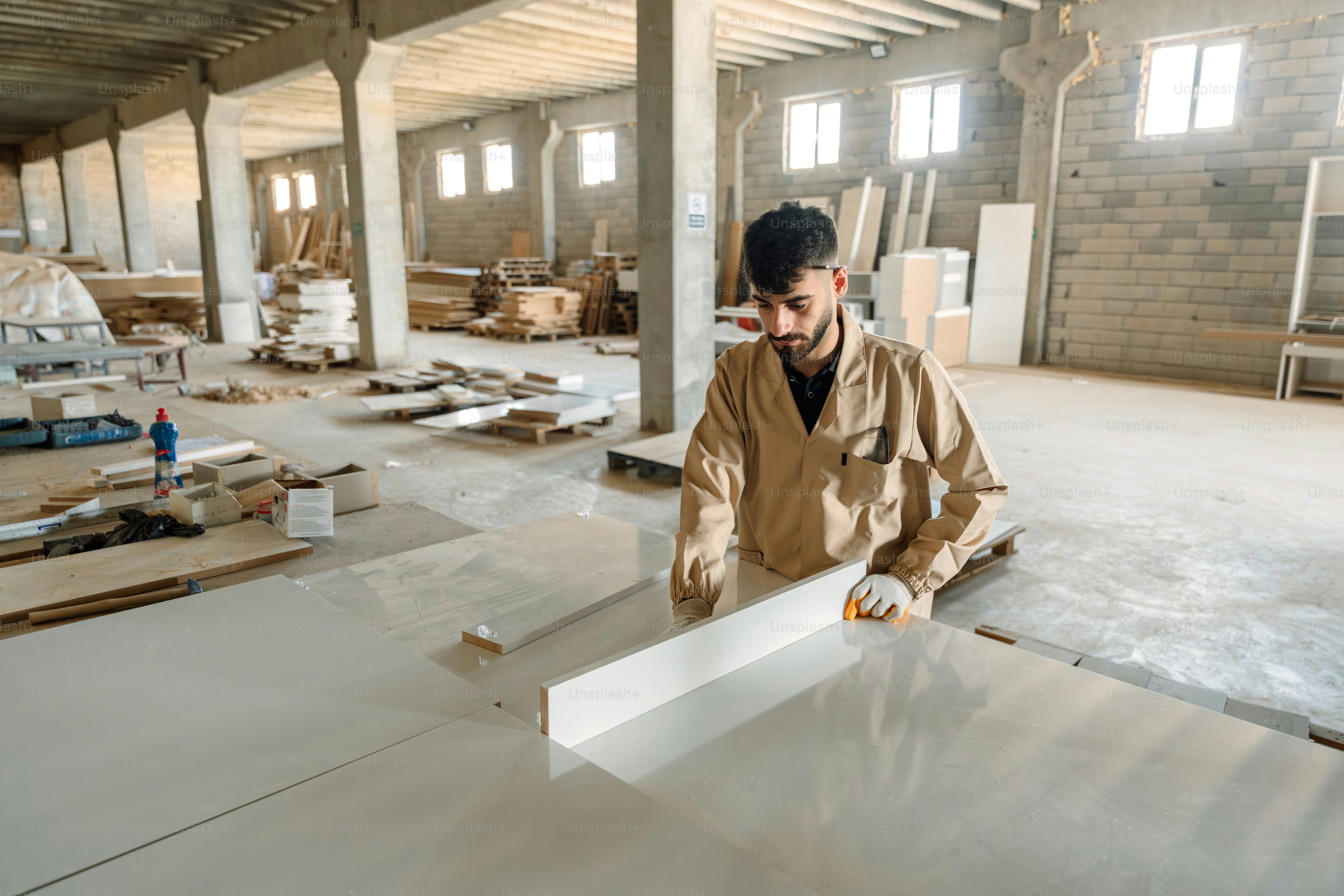Worker positioning a large panel in an industrial workshop.