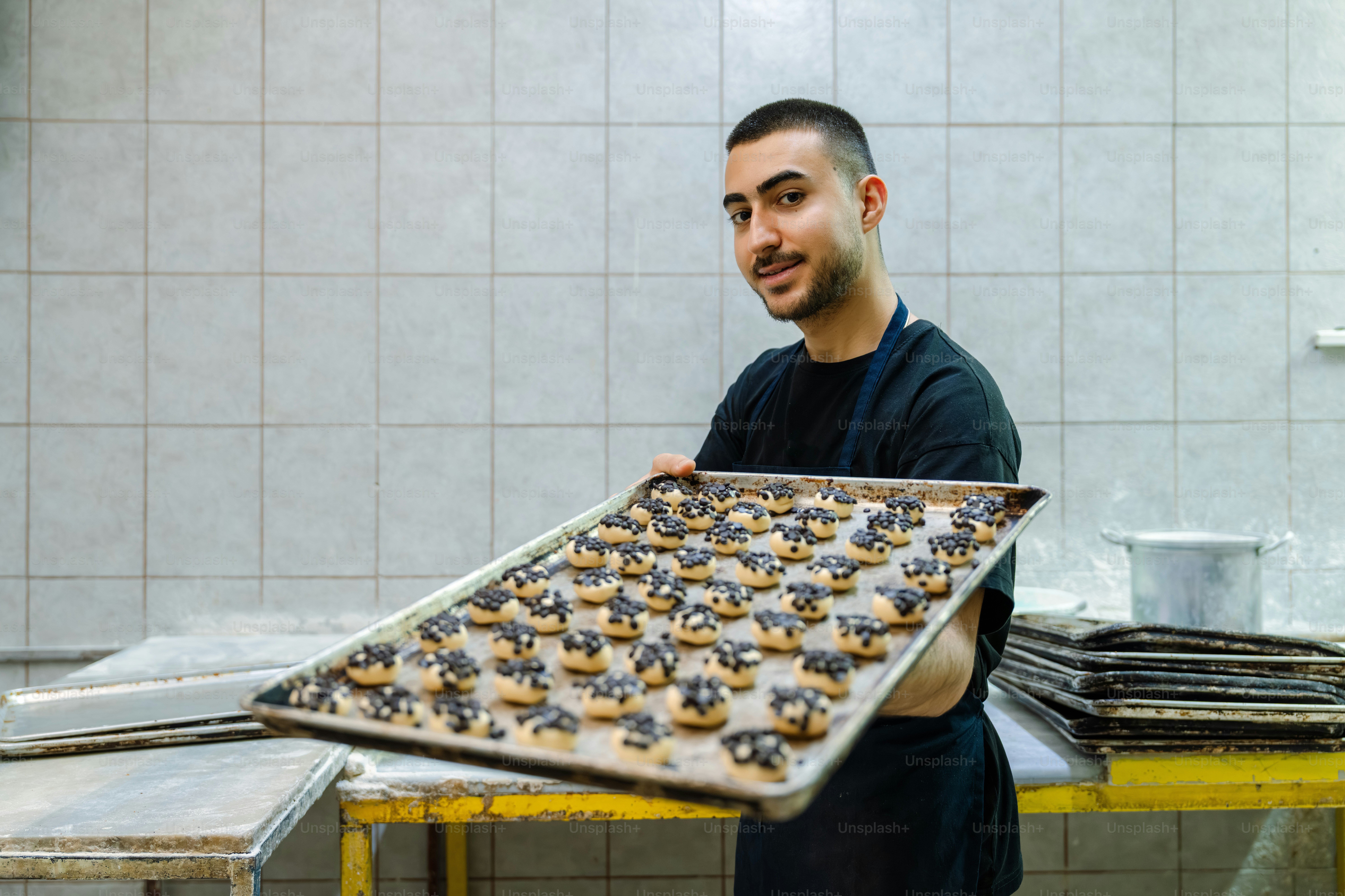 A smiling baker holds a tray of freshly baked pastries.